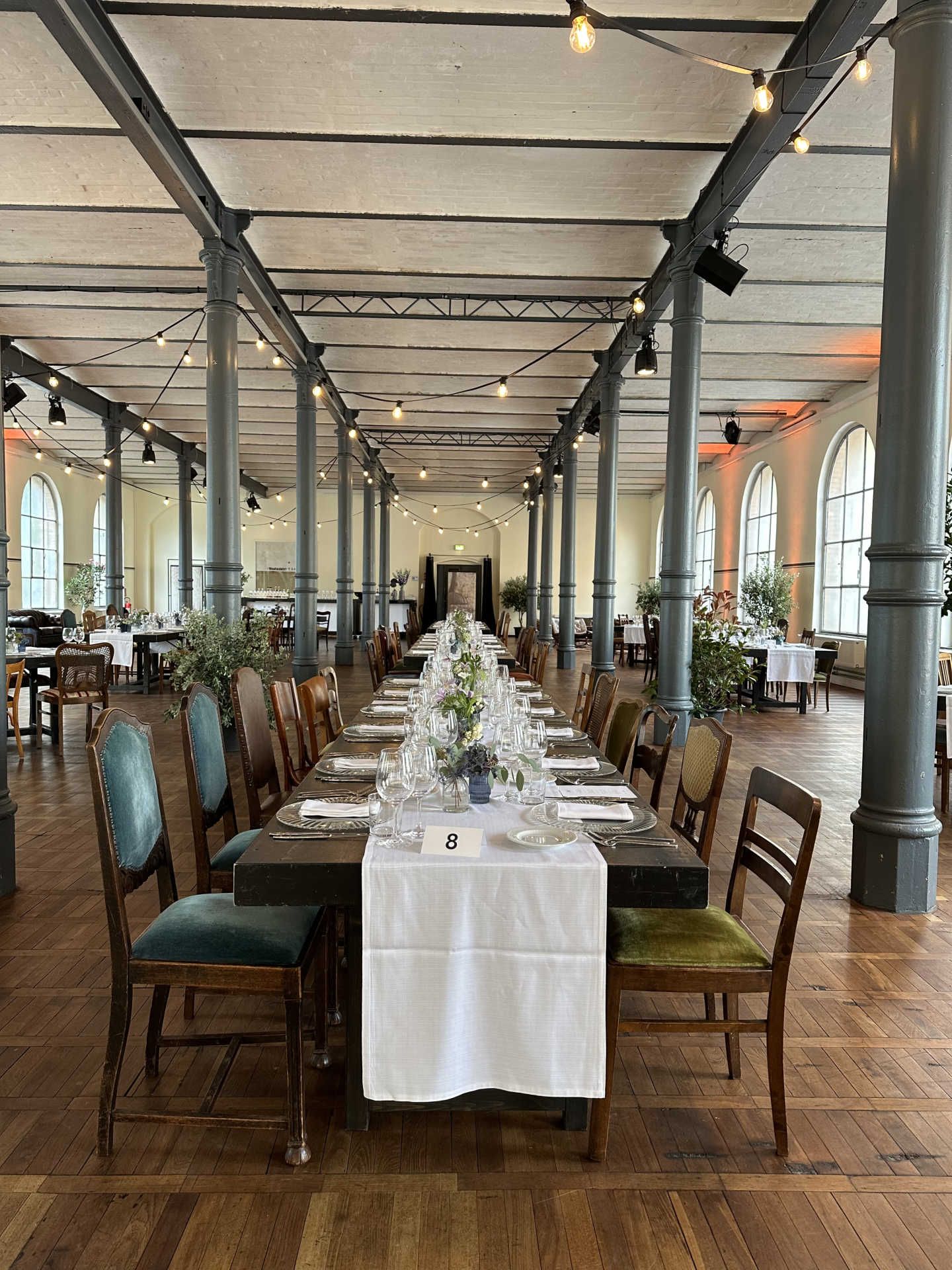 Festsaal mit langer gedeckter Tafel und weißem Tischläufer