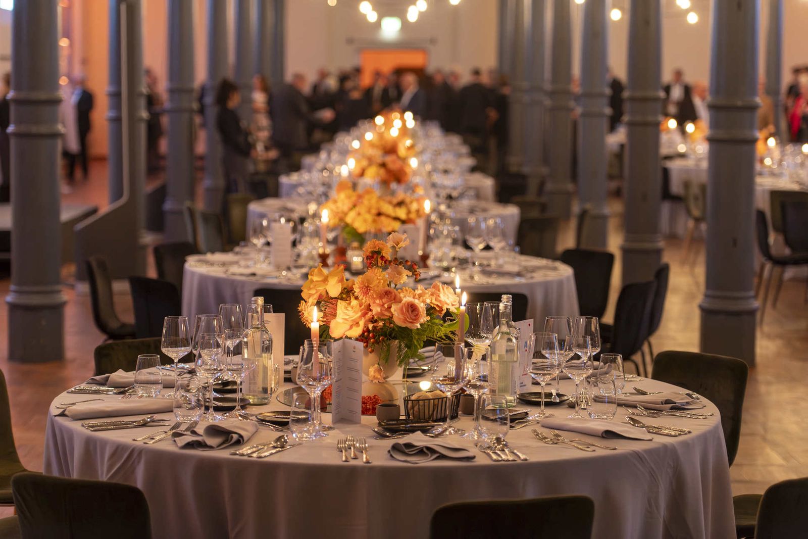 Weihnachtsfeier Location Berlin – festlich gedeckte Tafel mit Blumendekoration und Gästen im Magazin der Heeresbäckerei