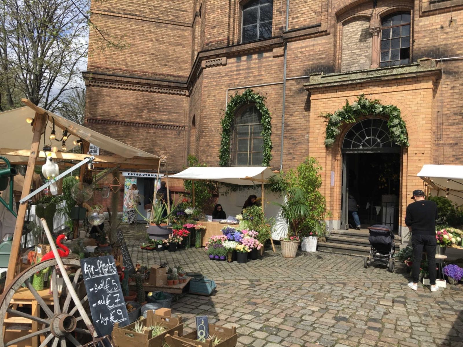 Forecourt of large brick building with market stands.