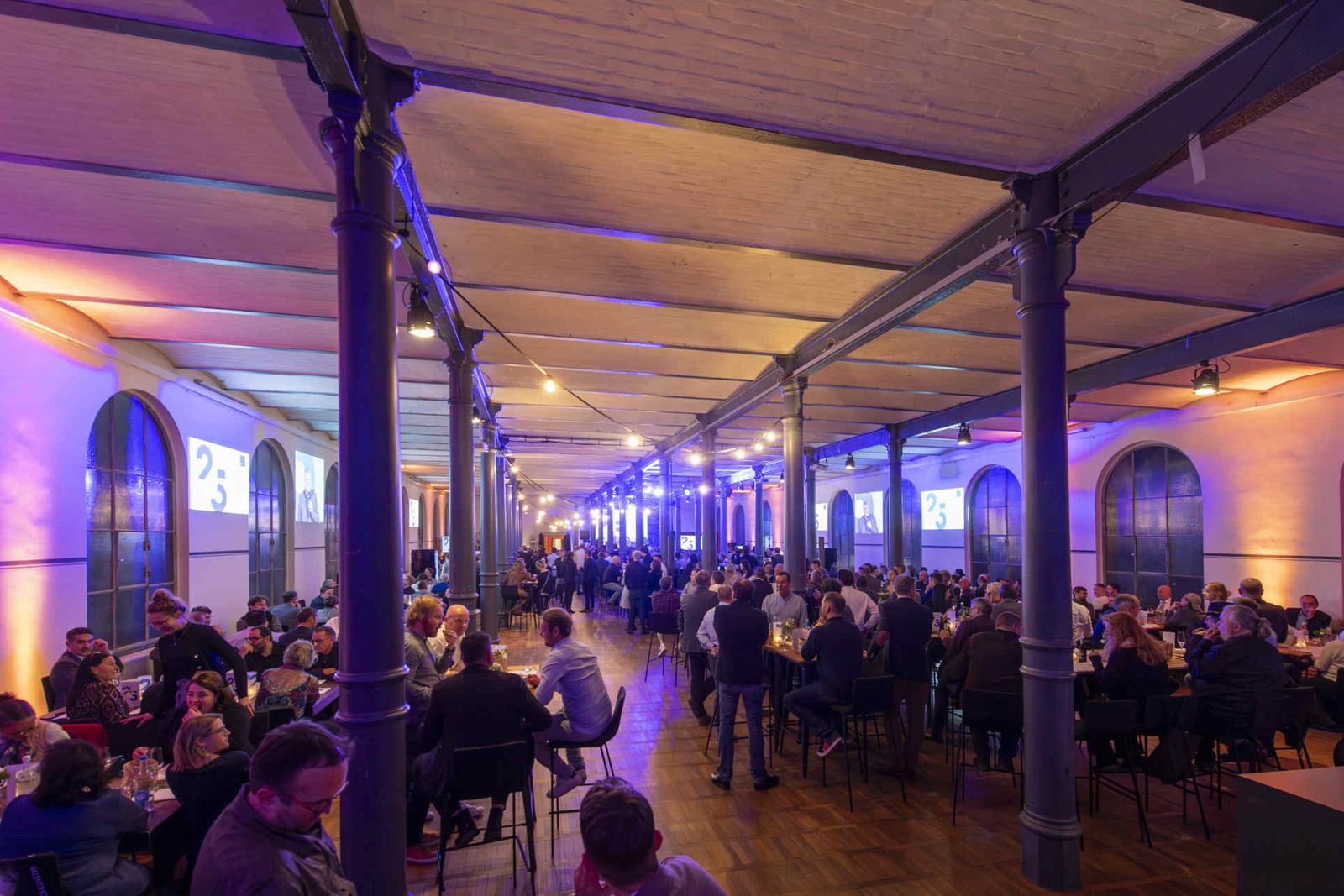 Großer Saal mit Holzboden und Stoffraumteiler und Bühne.