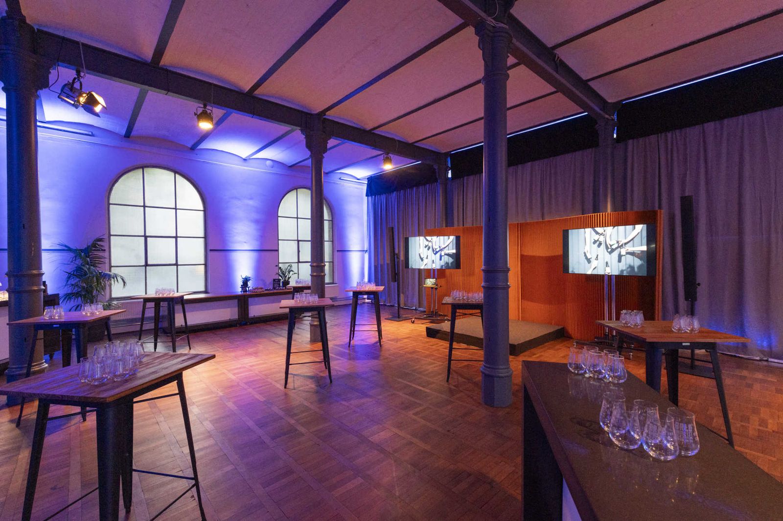 Eventlocation mit atmosphärischer Beleuchtung und Stehtischen.