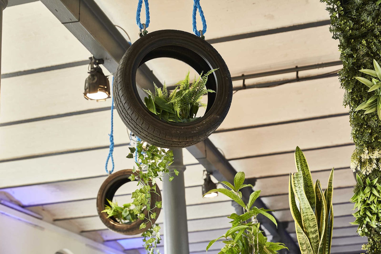 Hanging ceiling decoration with car tires and green plants.