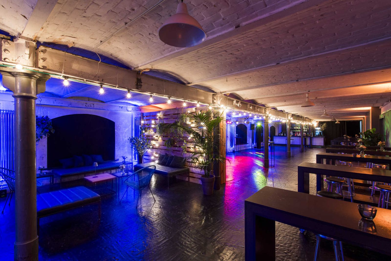 Partyraum mit Lichterketten, Loungemobiliar und Palettenwand.