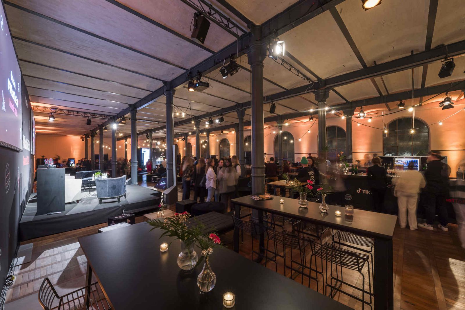 Eventsaal mit atmosphärischer Beleuchtung und Menschen während einer Veranstaltung.