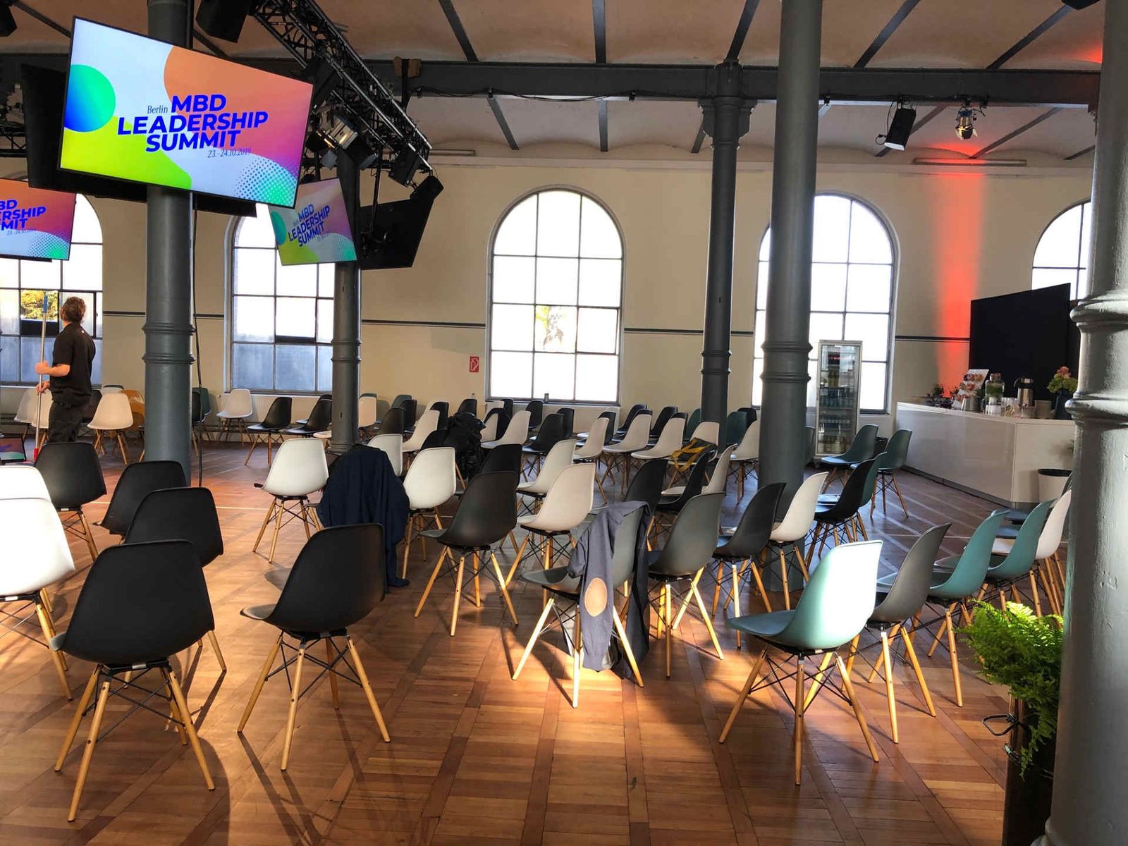 Stuhlmix im Saal mit bunten Monitoren an Säulen