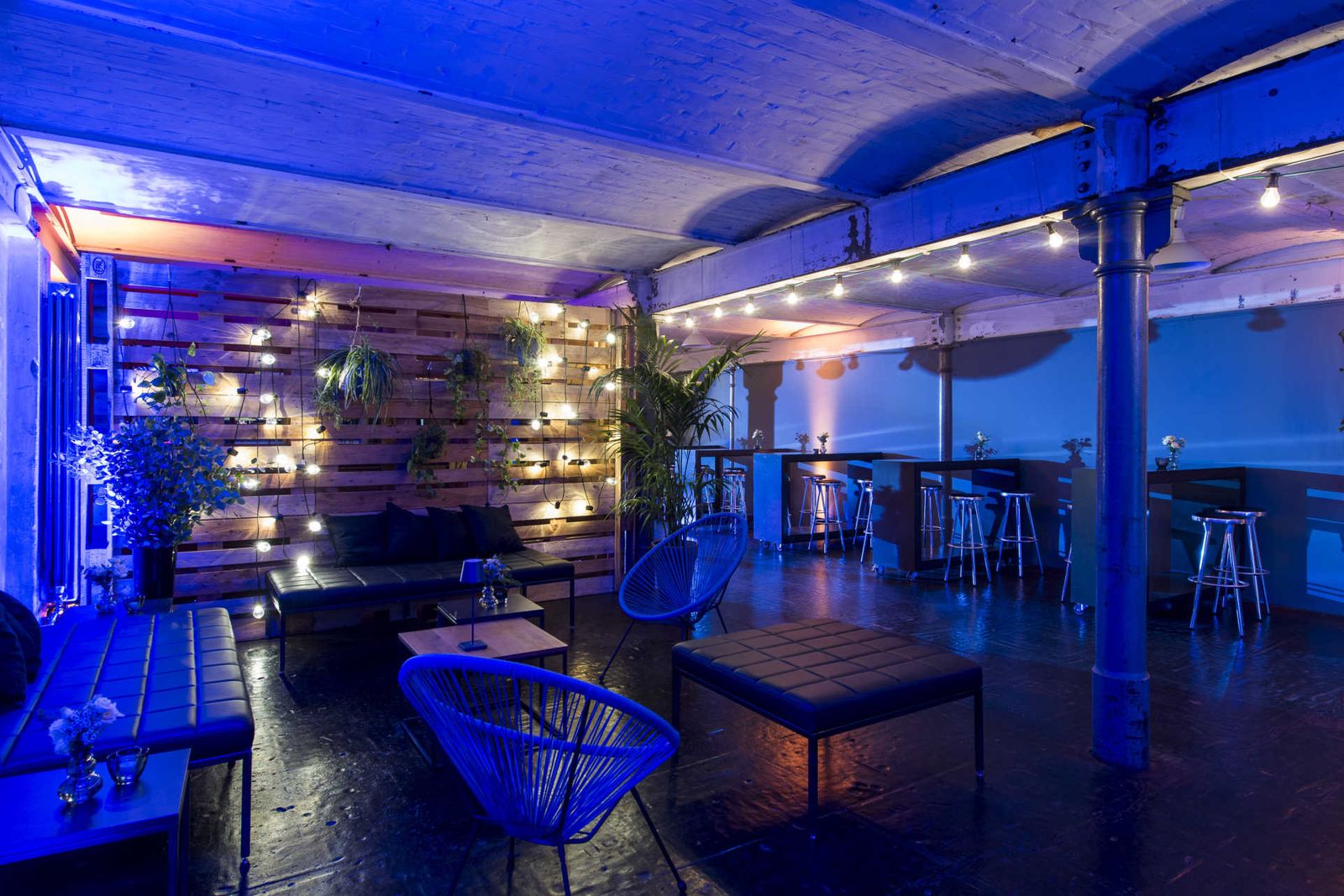 Partyraum mit Lichterketten, Loungemobiliar und Palettenwand.
