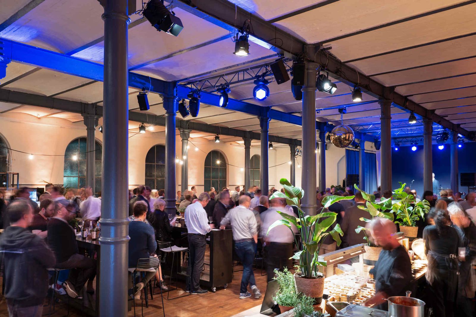 Eventsaal mit atmosphärischer Beleuchtung und Menschen während einer Veranstaltung.
