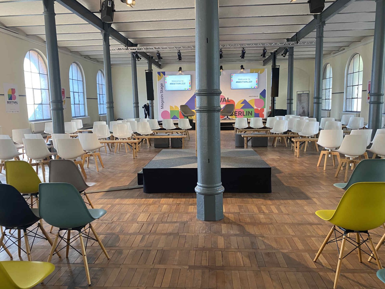 bunter Stuhlmix im Saal zur Bühne gerichtet mit großem, bunten Backdrop