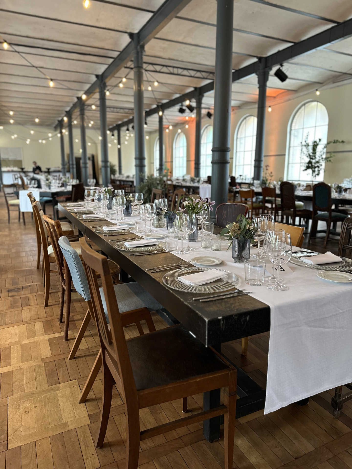 Festsaal mit langer gedeckter Tafel und weißem Tischläufer