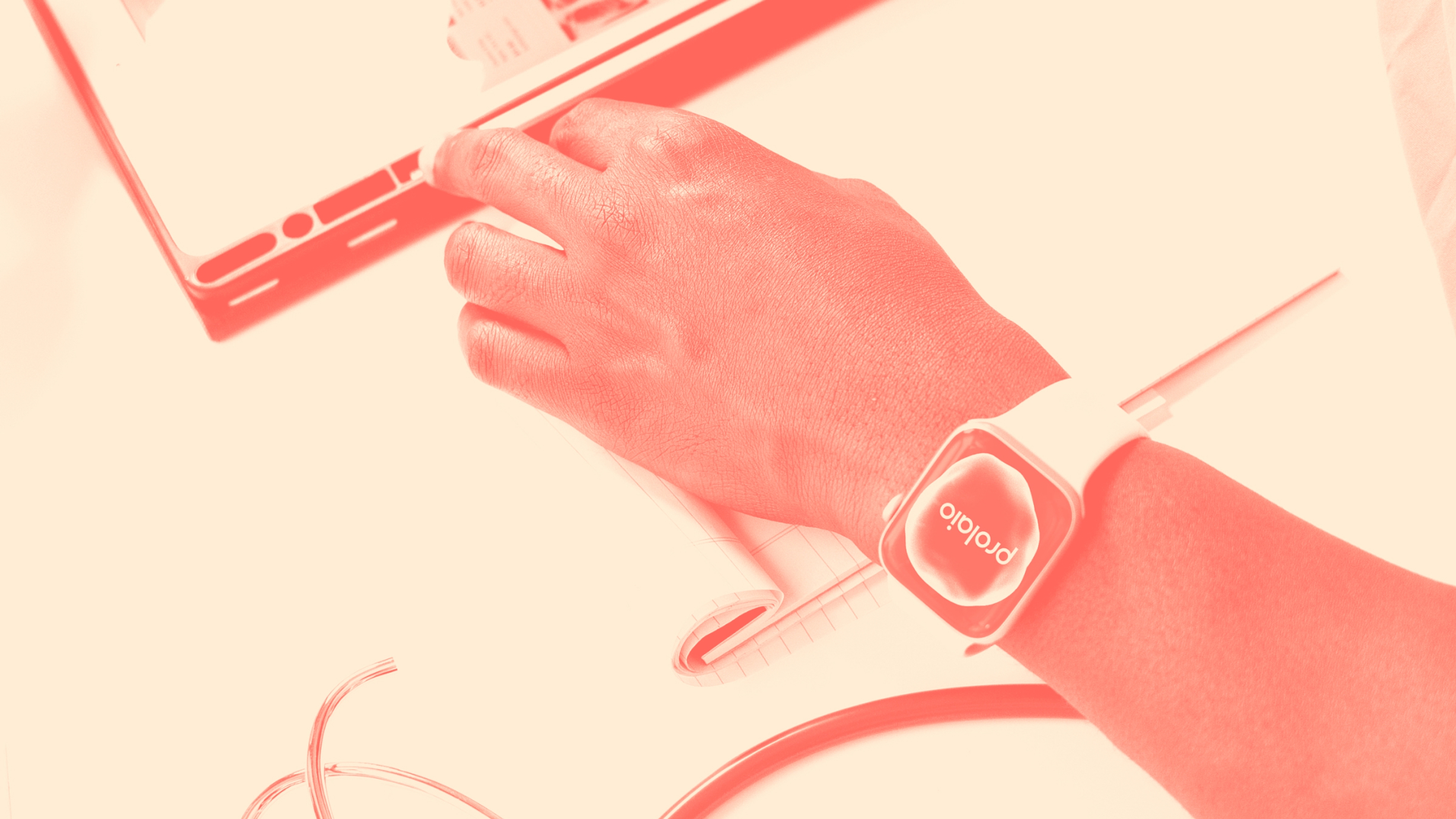 A person's hand showing the Prolaio logo on their Apple watch reaching for a tablet