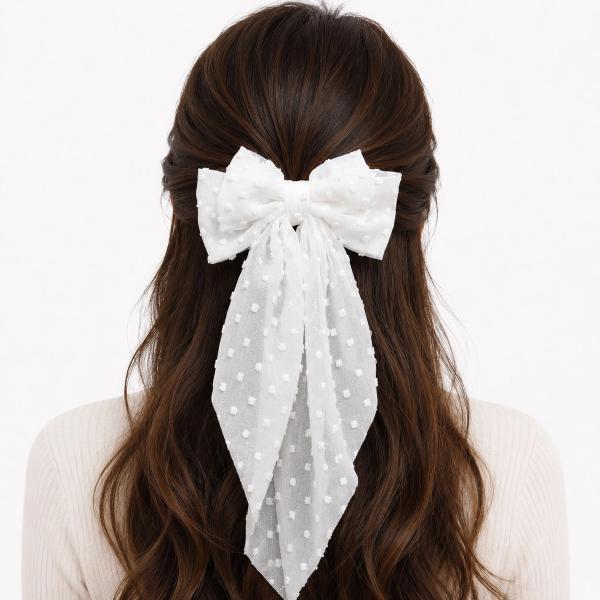 A large white chiffon polka dot bow clip with long flowing tails worn in a half-up hairstyle on a dark-haired model.