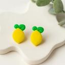 A pair of bright yellow lemon-shaped polymer clay stud earrings with green leaf details displayed on a white ceramic tray.