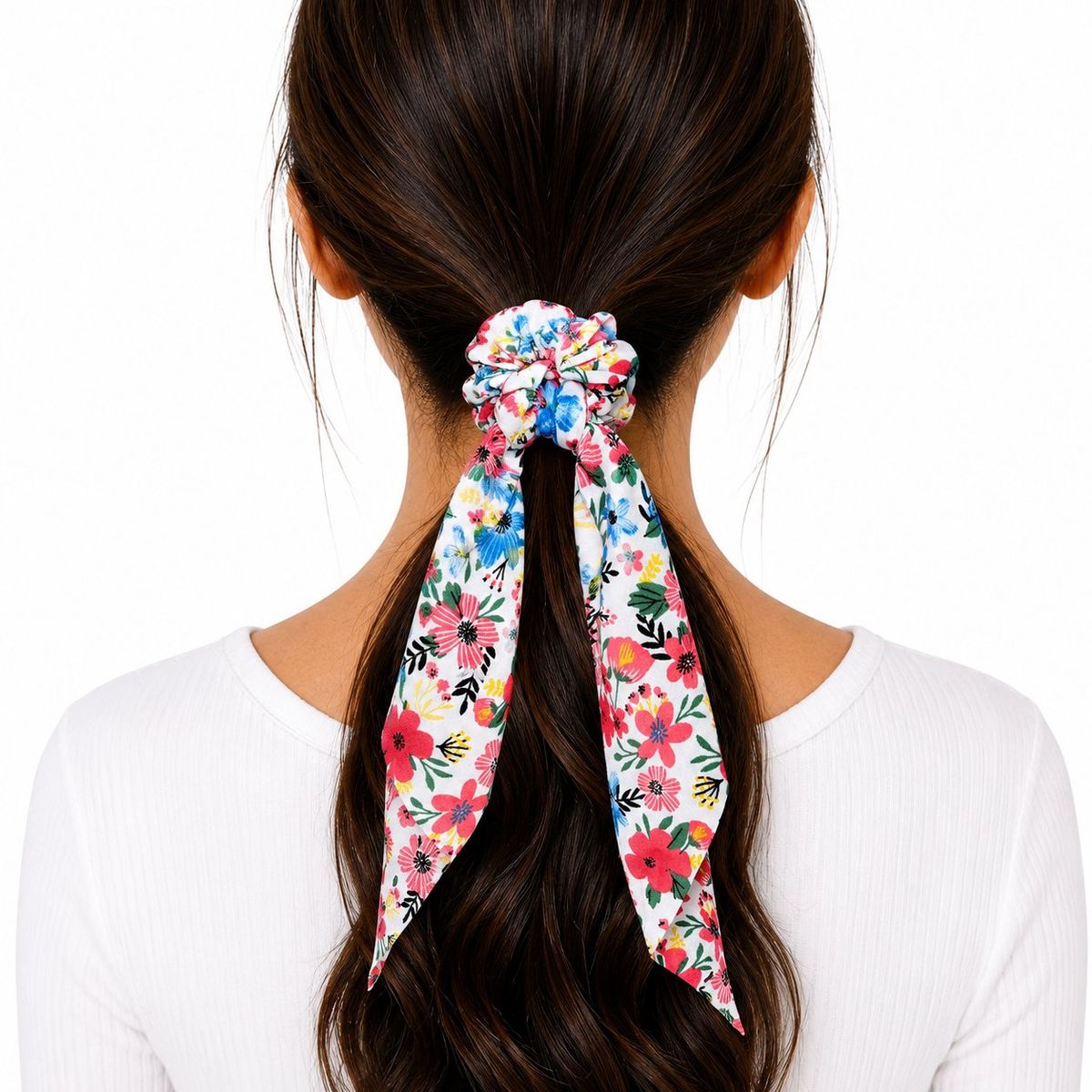 Back view of a woman wearing a white floral scarf scrunchie in her dark ponytail, with long printed fabric tails hanging down.