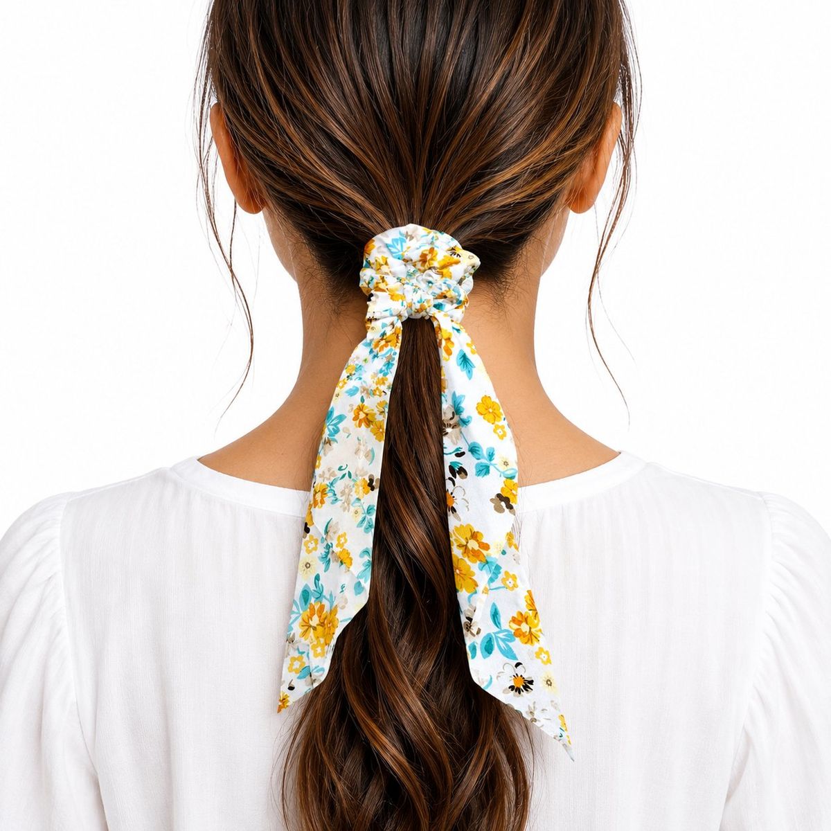 Back view of a woman wearing a white floral scarf scrunchie with yellow and teal flowers in her ponytail.