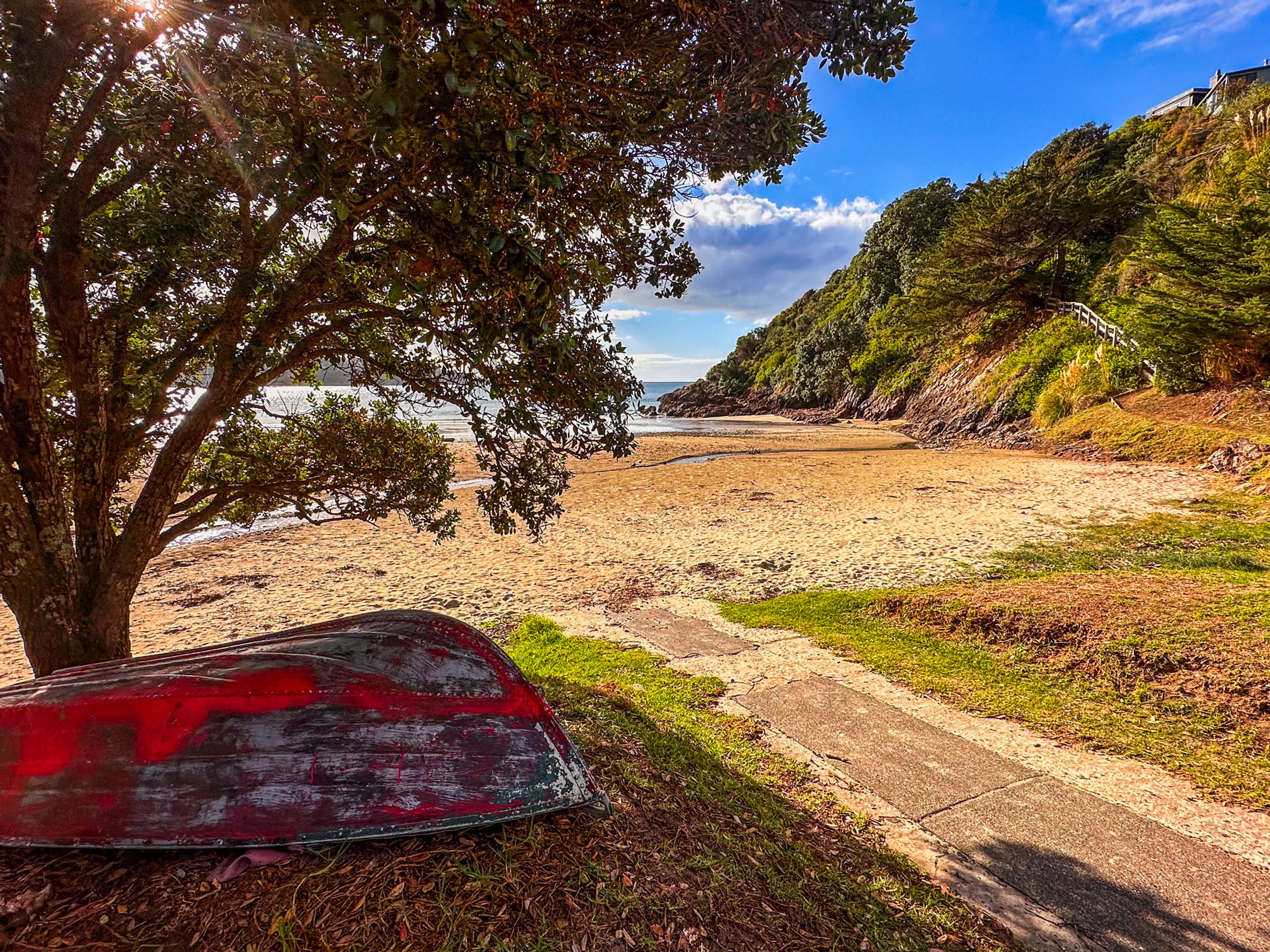 A upturned dinghy under a tree at Little Oneroa Beach
