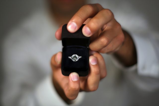 Main tenant une bague de fiançailles en gros plan – symbole d’une demande en mariage romantique et inoubliable.