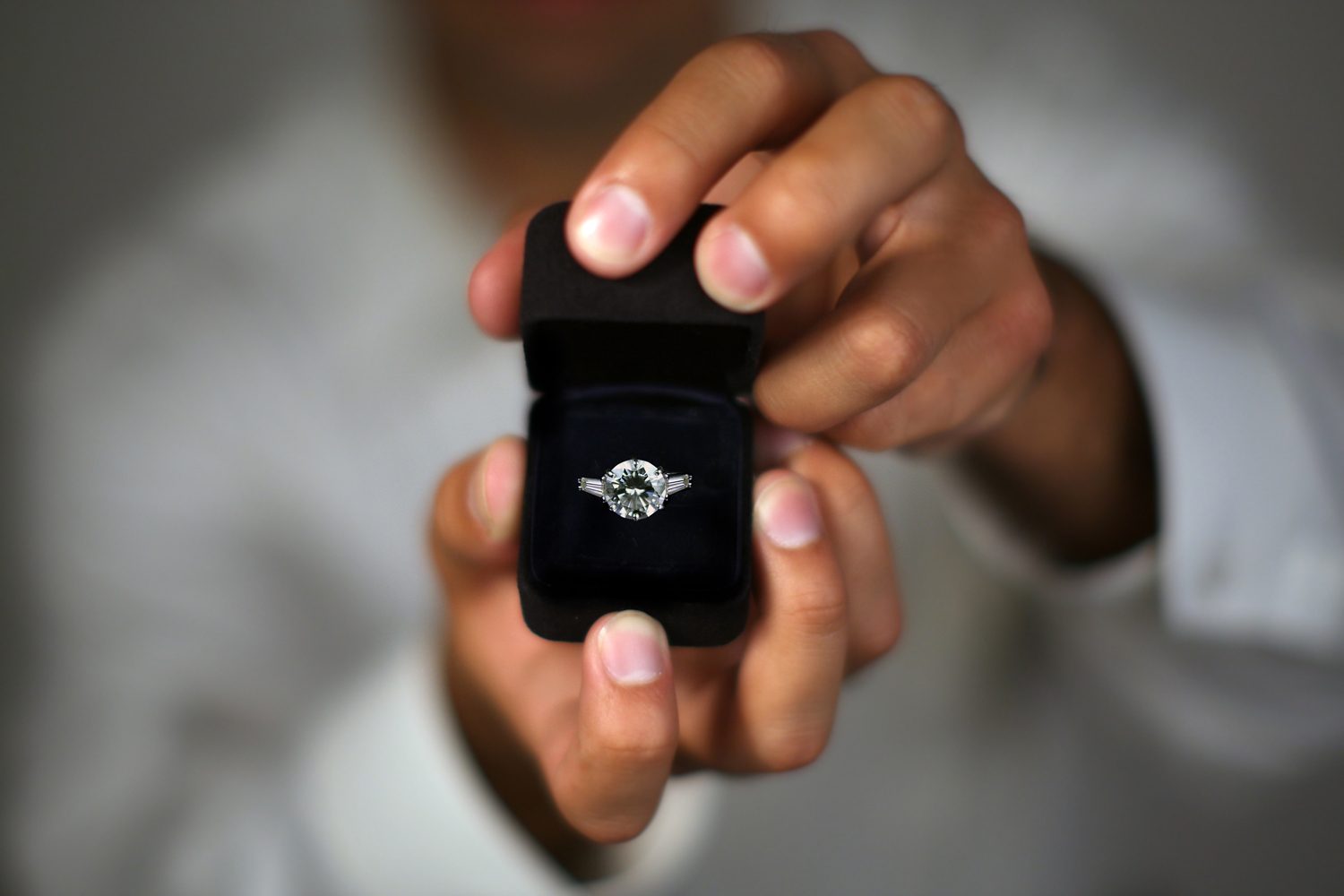 Main tenant une bague de fiançailles en gros plan – symbole d’une demande en mariage romantique et inoubliable.