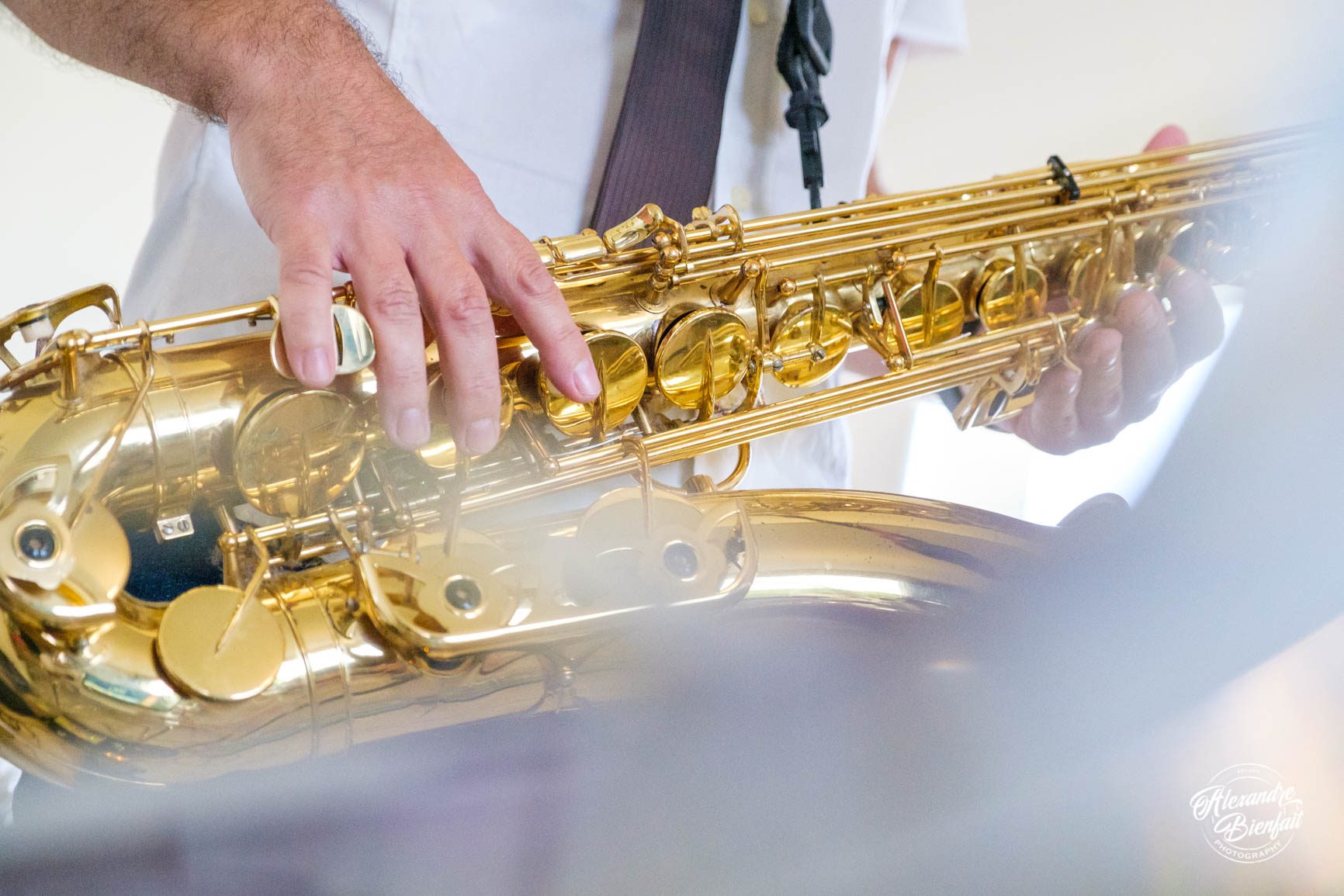 Gros plan sur les mains d’Alex posées sur les clés du saxophone, lumière claire