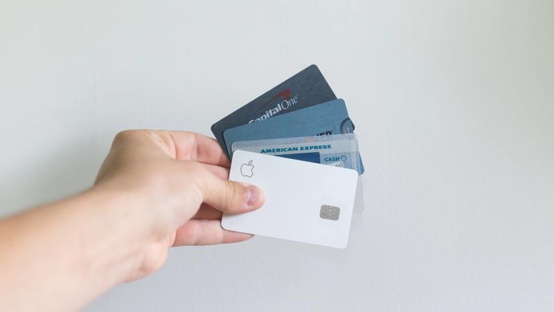 a hand holding four credit card with business debt