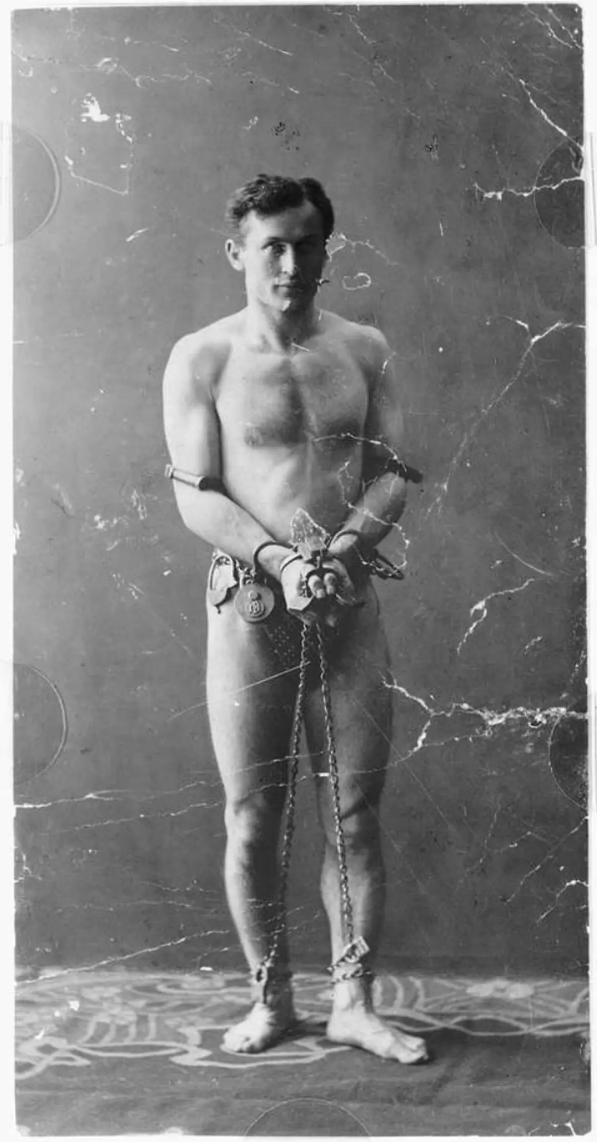 Houdini poserer bar overkropp med kropp og bein lenket sammen — reklamefoto brukt for å bevise at han ikke gjemte verktøy.