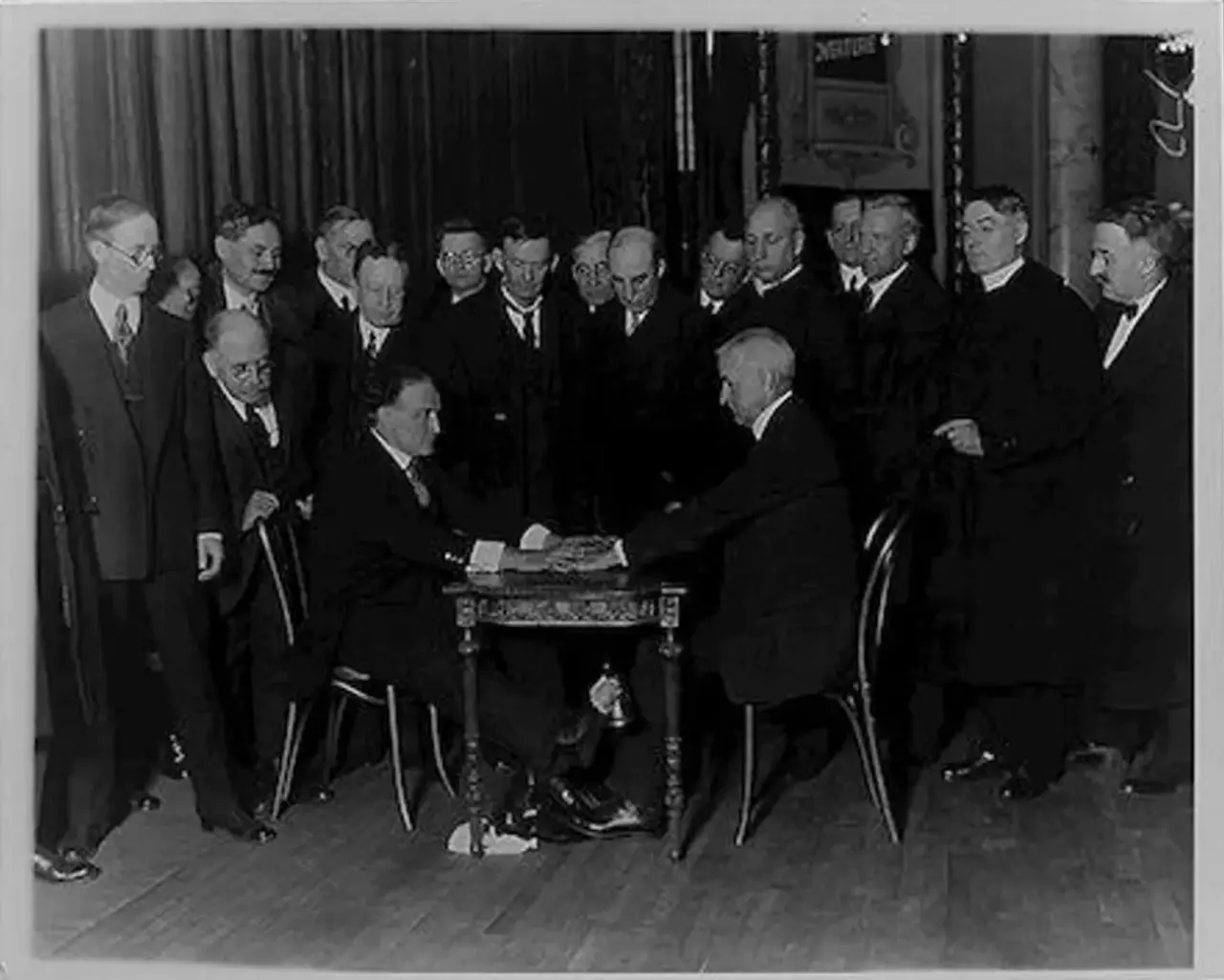 Houdini avslører et spiritistisk medium under en seanse — mediet strekker foten ut for å ringe en bjelle under bordet. Library of Congress.