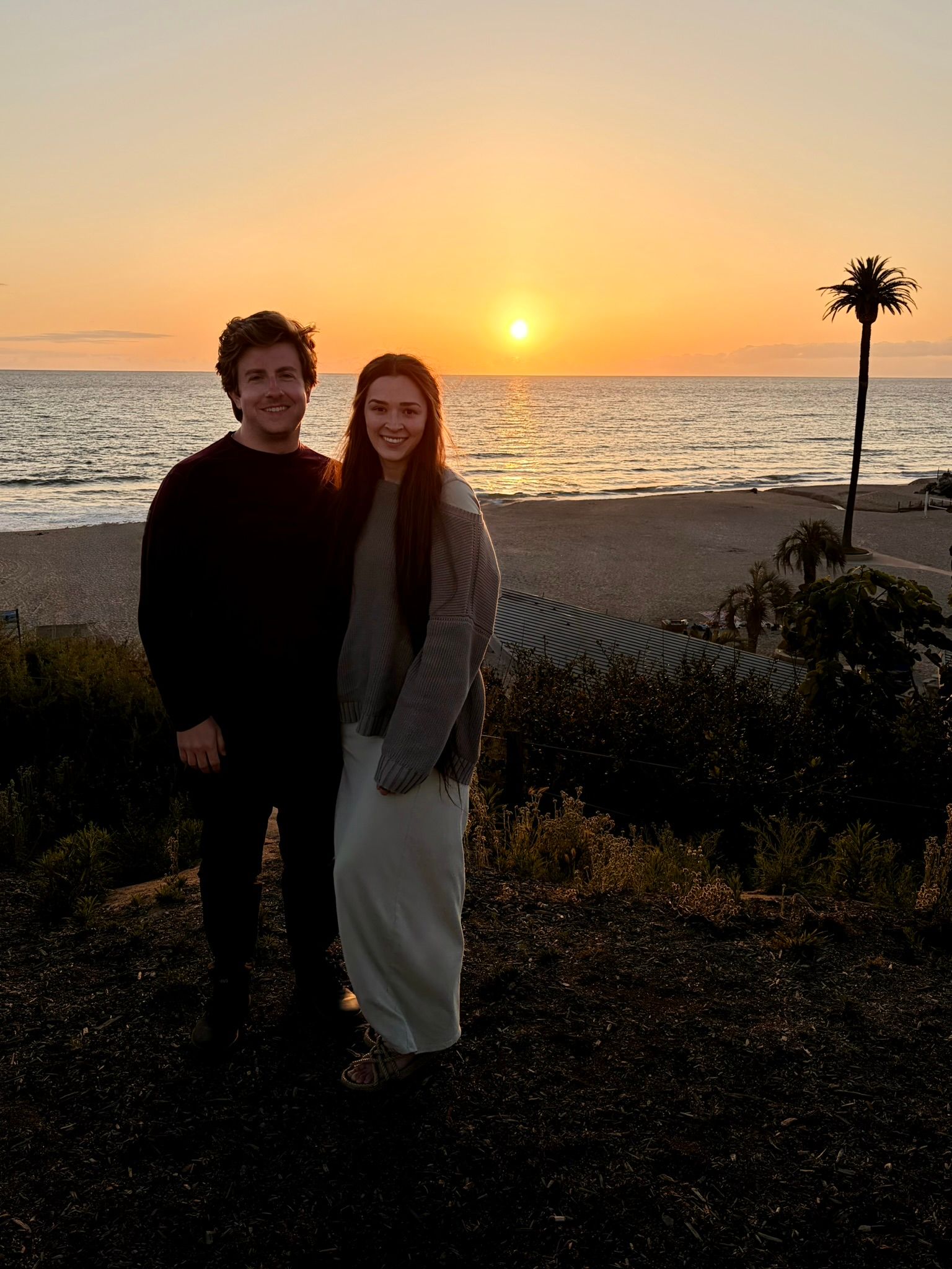 Timothy Reavis with a companion by the ocean at sunset