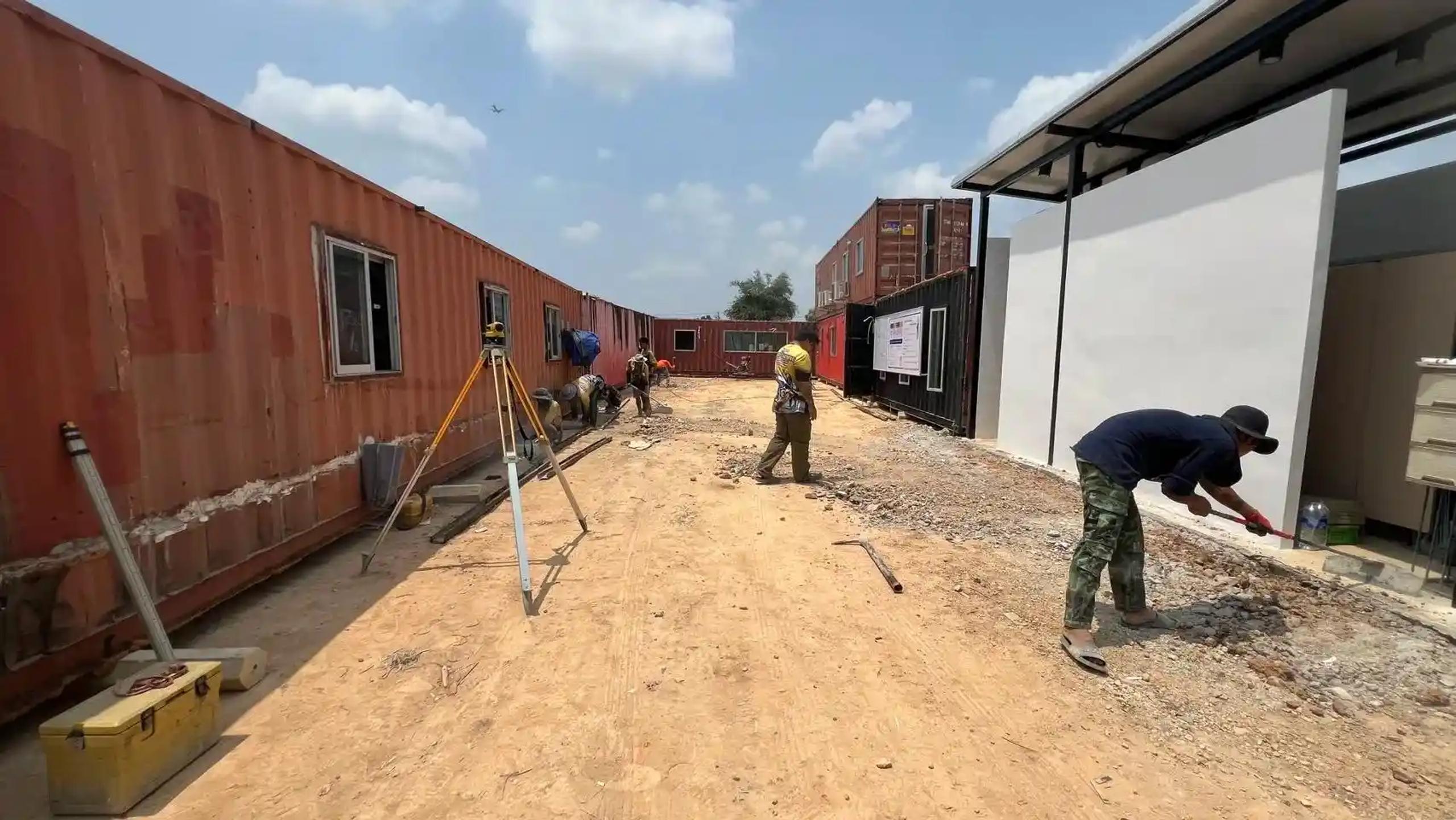 ทีมช่างสำรวจและก่อสร้างโครงการดัดแปลงตู้คอนเทนเนอร์เป็นอาคาร | Construction team surveying a shipping-container-to-building conversion project