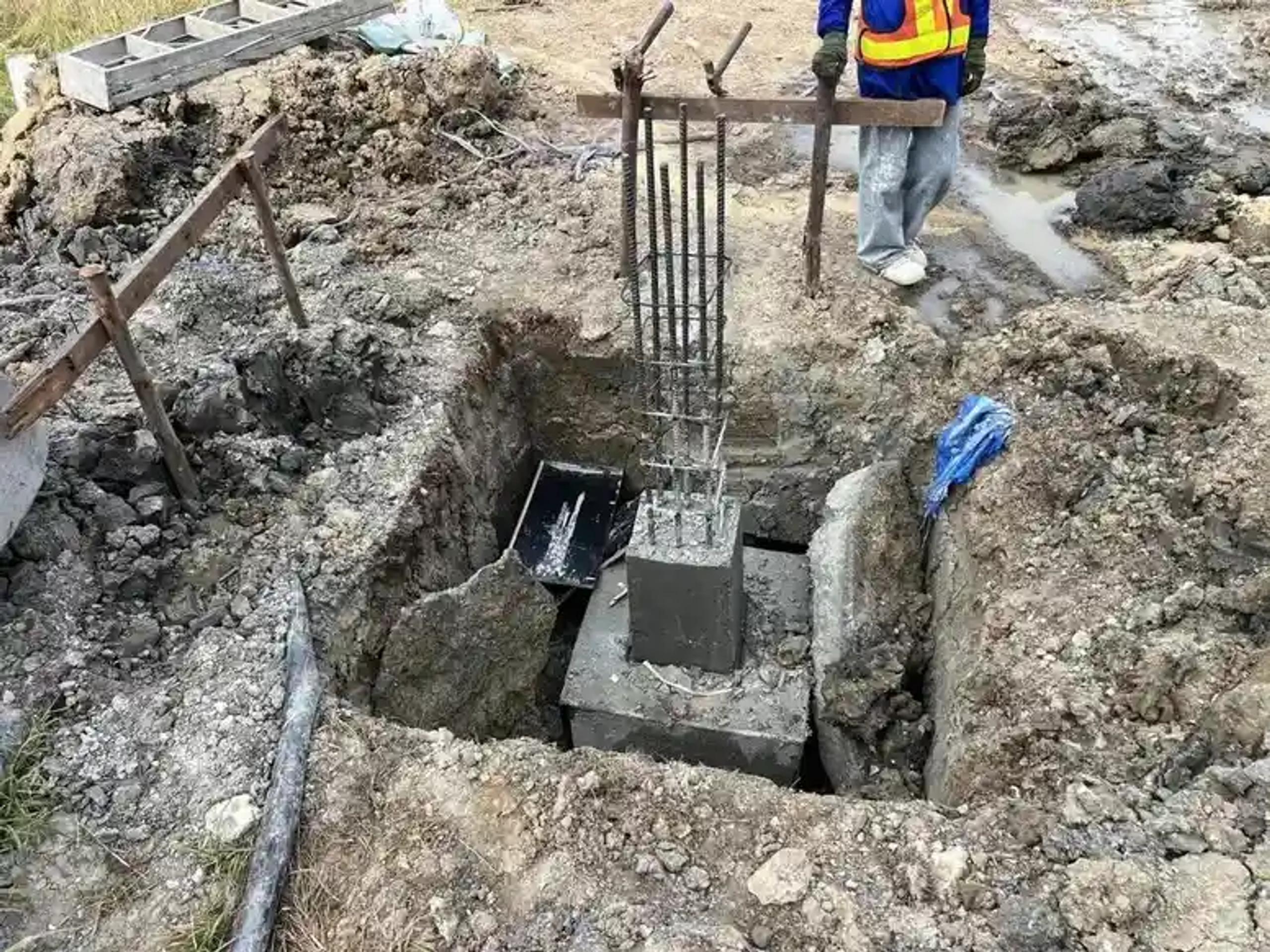 งานขุดหลุมและเทฐานรากคอนกรีตเสริมเหล็กสำหรับโครงสร้าง | Excavated pit with reinforced concrete footing for a structural column
