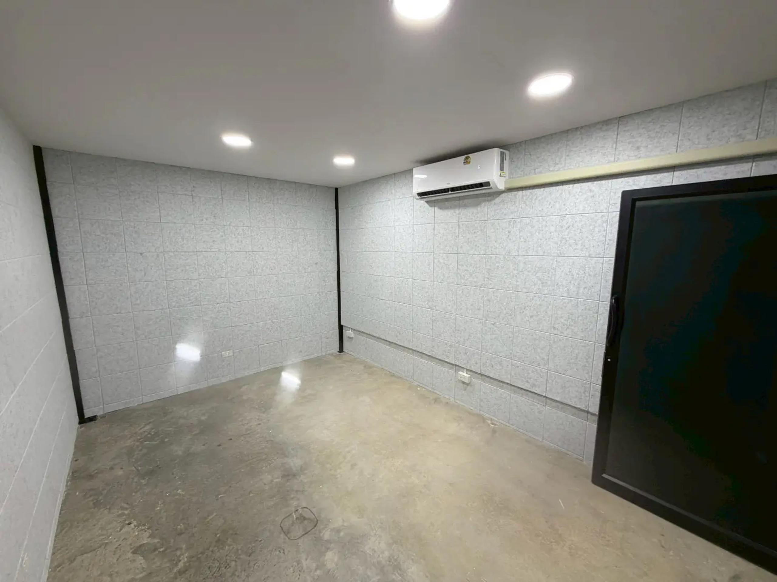 ห้องสำนักงานชั้นลอยที่ตกแต่งเสร็จ ผนังบุแผ่นลายหินสีขาว ฝ้าเรียบพร้อมดาวน์ไลท์ และแอร์ติดผนัง | Finished mezzanine office with white stone-pattern wall panels, downlights and a wall-mounted air conditioner