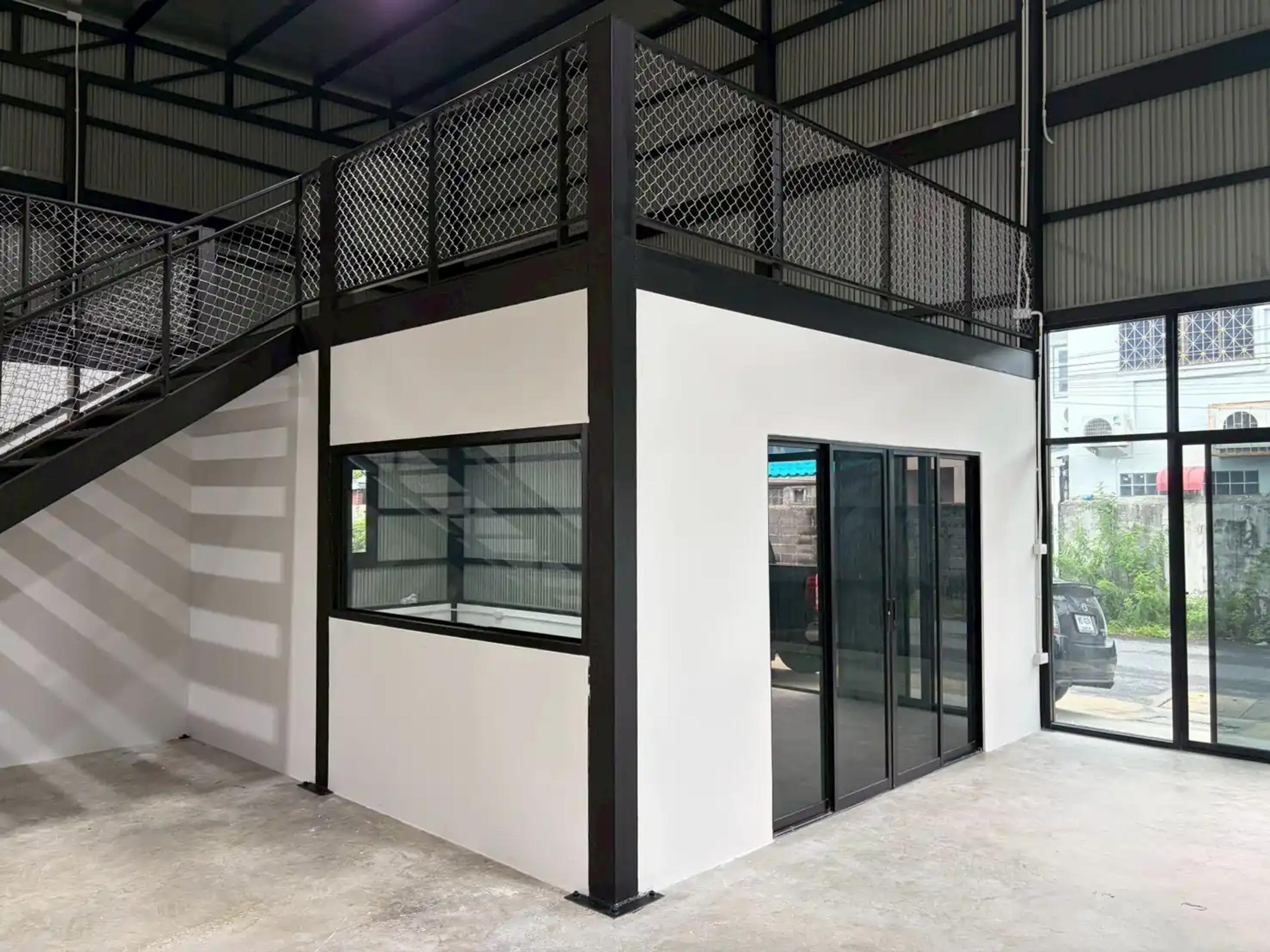 ห้องสำนักงานใต้ชั้นลอยที่ก่อสร้างเสร็จ พร้อมหน้าต่างกระจก ประตูบานเลื่อน และผนังกระจกด้านหน้าอาคาร | Completed office room under the mezzanine with glass windows, a sliding door and the building front glass wall