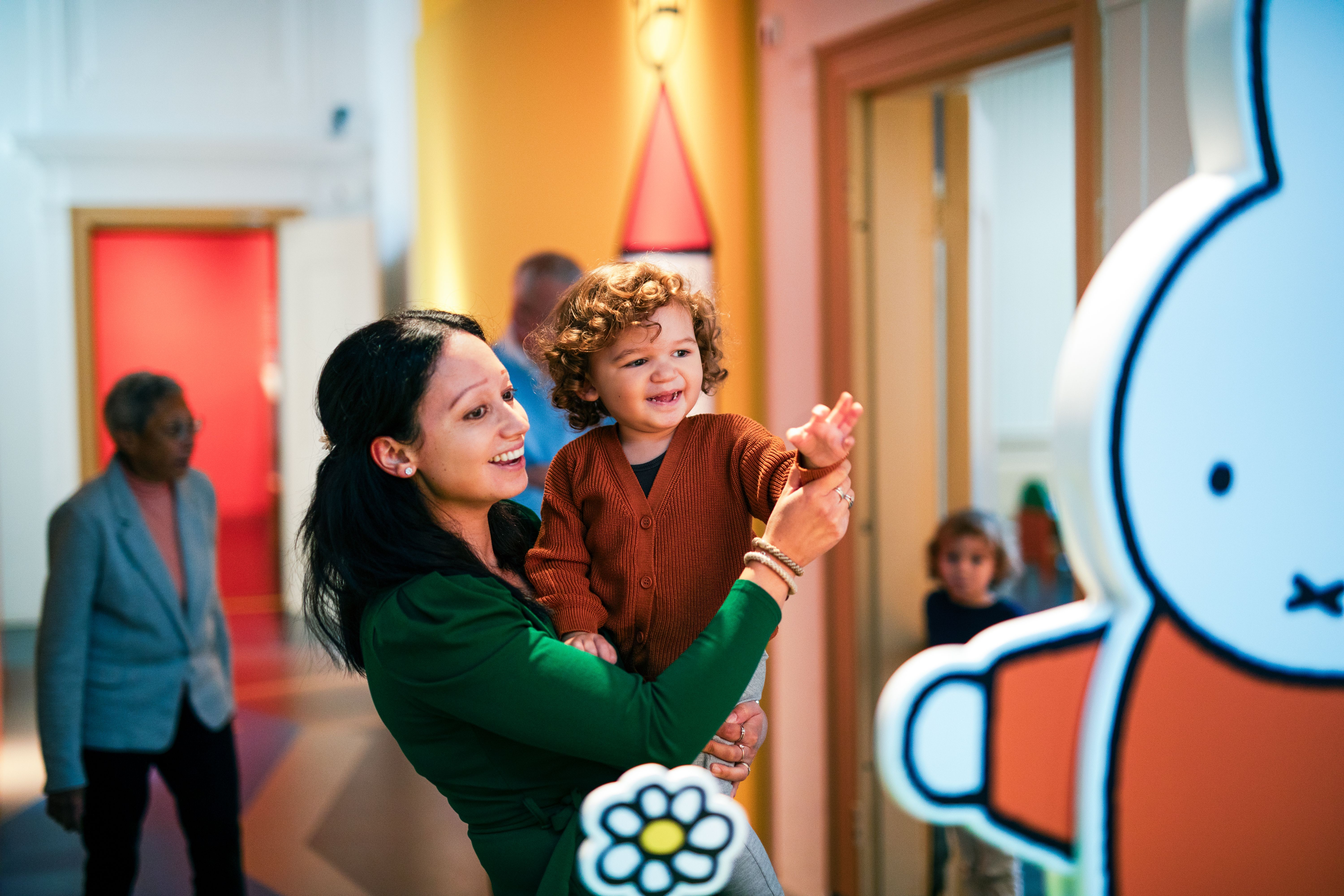 volwassene en kind zwaaien naar nijntje in het museum