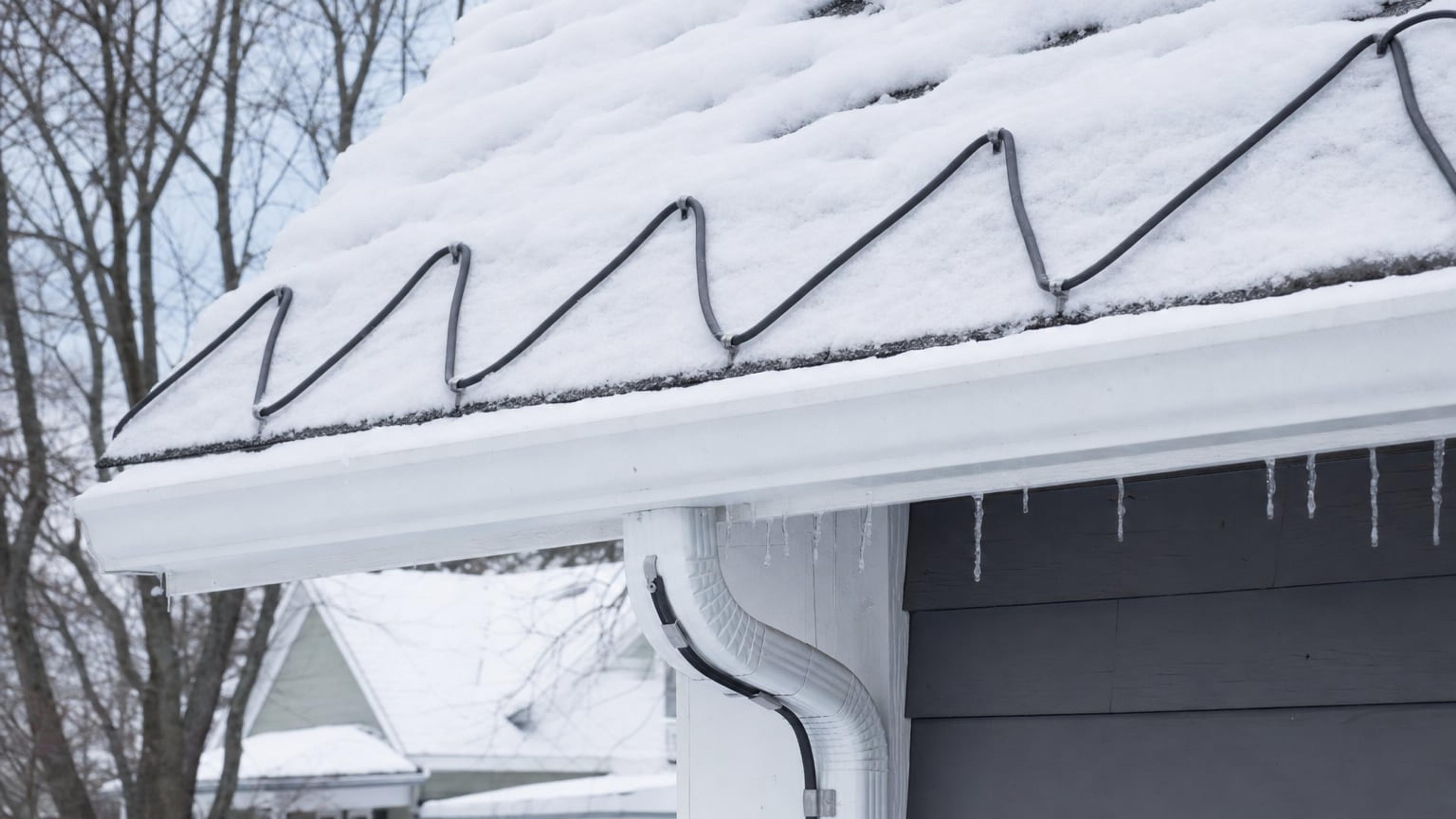 Snow-covered roof edge with a heat cable installed in a zigzag pattern along the eave and through the gutter