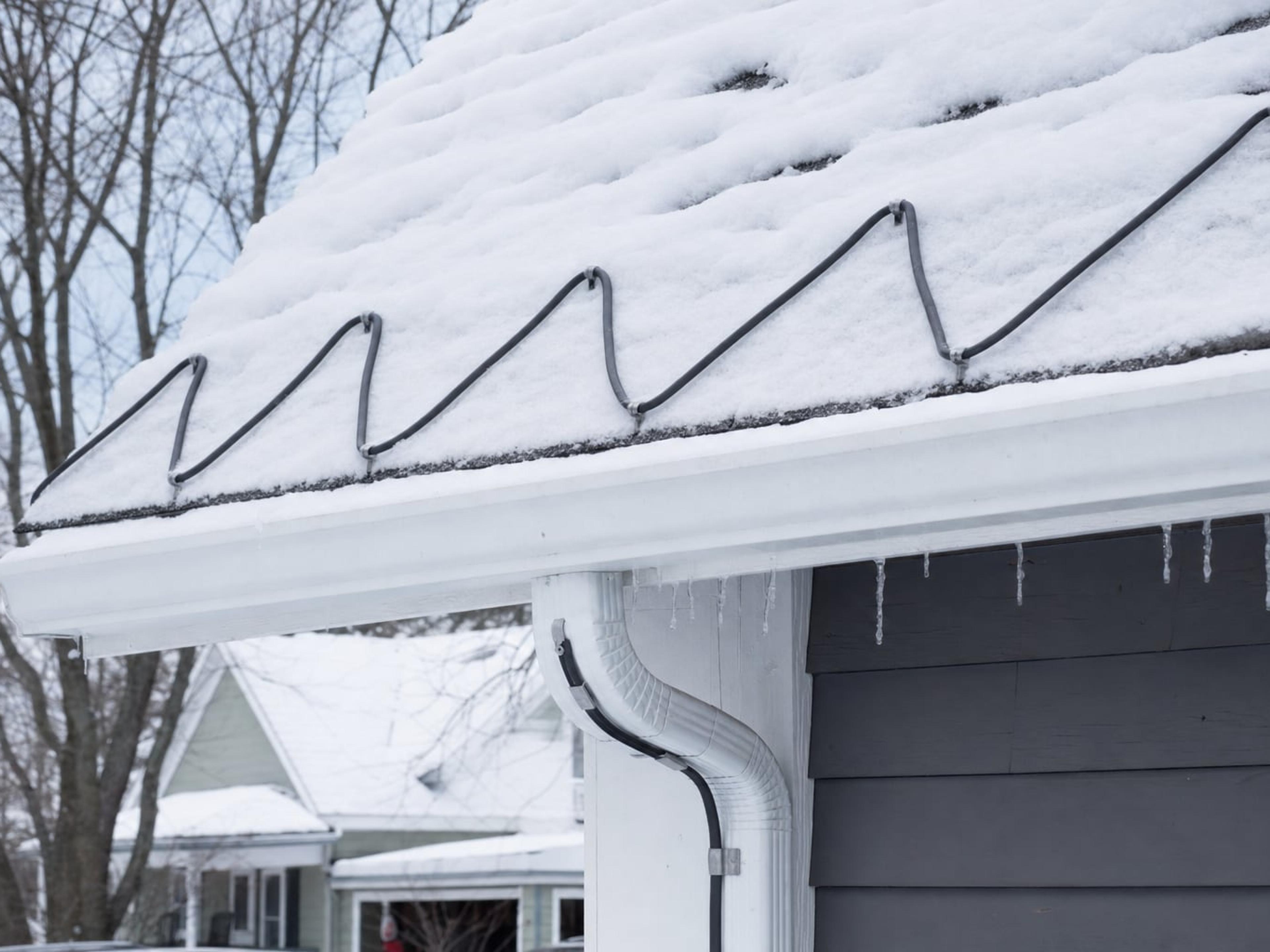 Snow-covered roof edge with a heat cable installed in a zigzag pattern along the eave and through the gutter