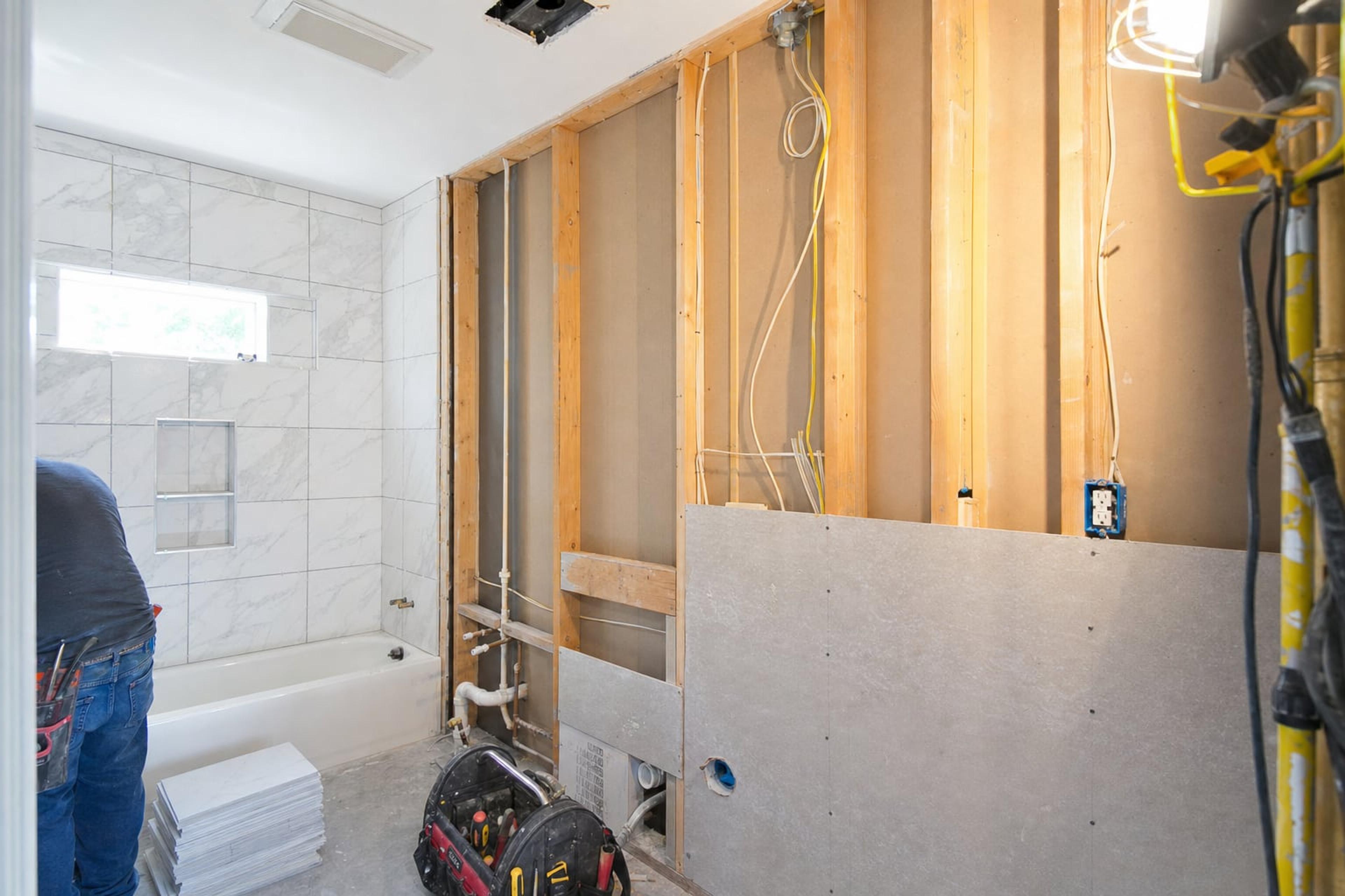 Bathroom remodel with exposed studs, new wiring for a vanity light and fan, and a GFCI outlet box beside the vanity