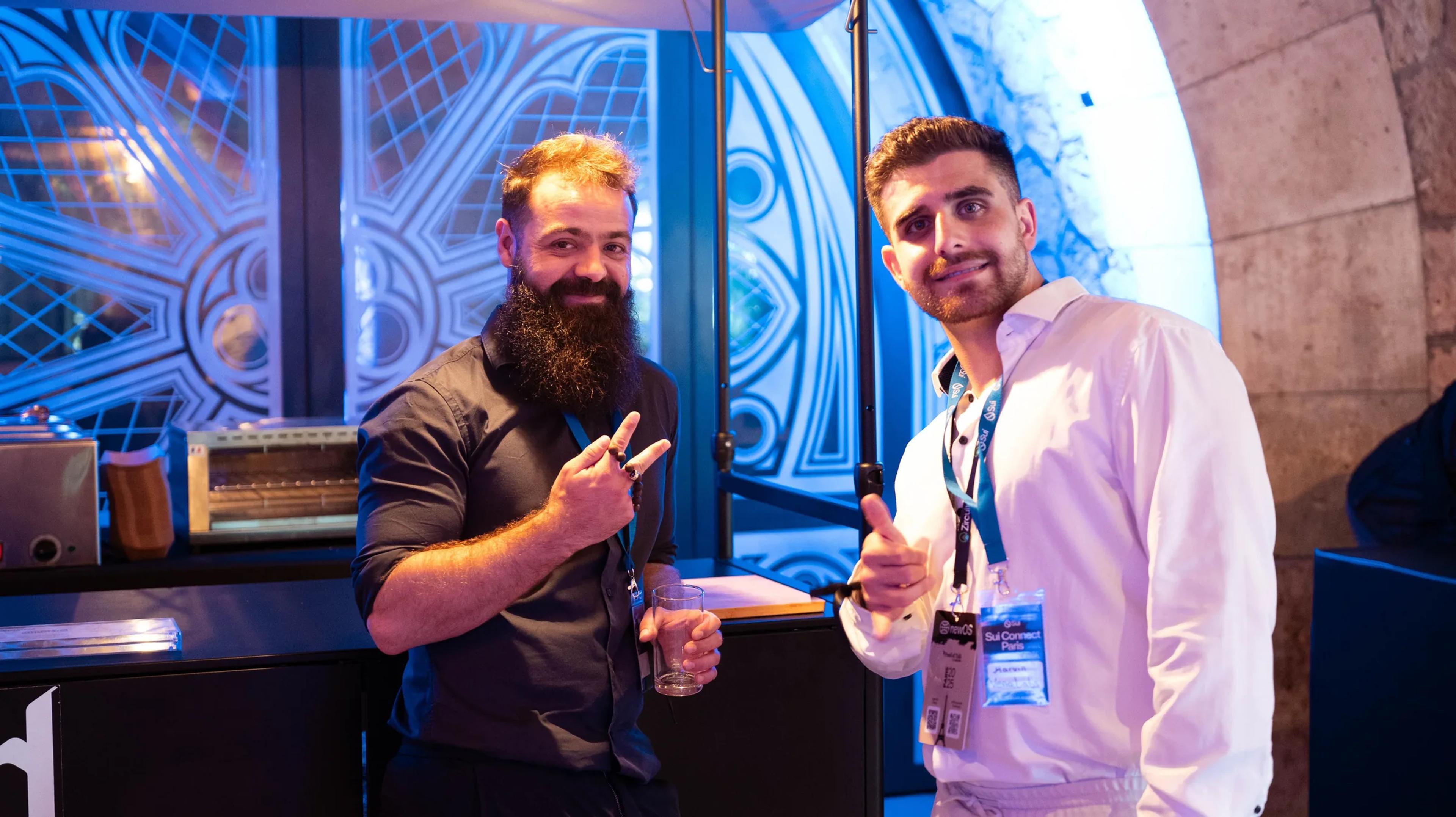 Two attendees posing with a thumbs-up at Sui Connect Paris