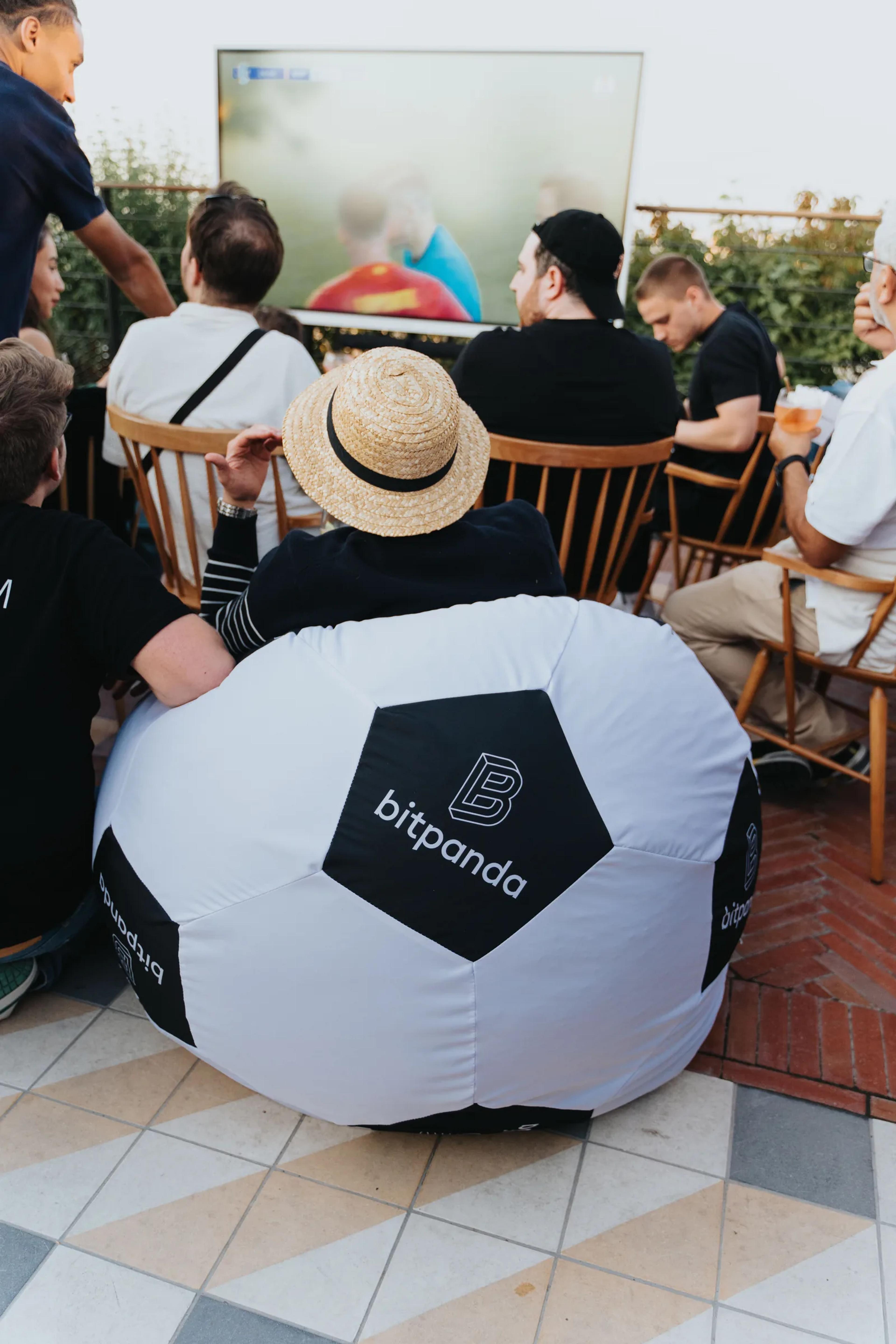 Guests watching a screen from a Bitpanda bean bag on the rooftop