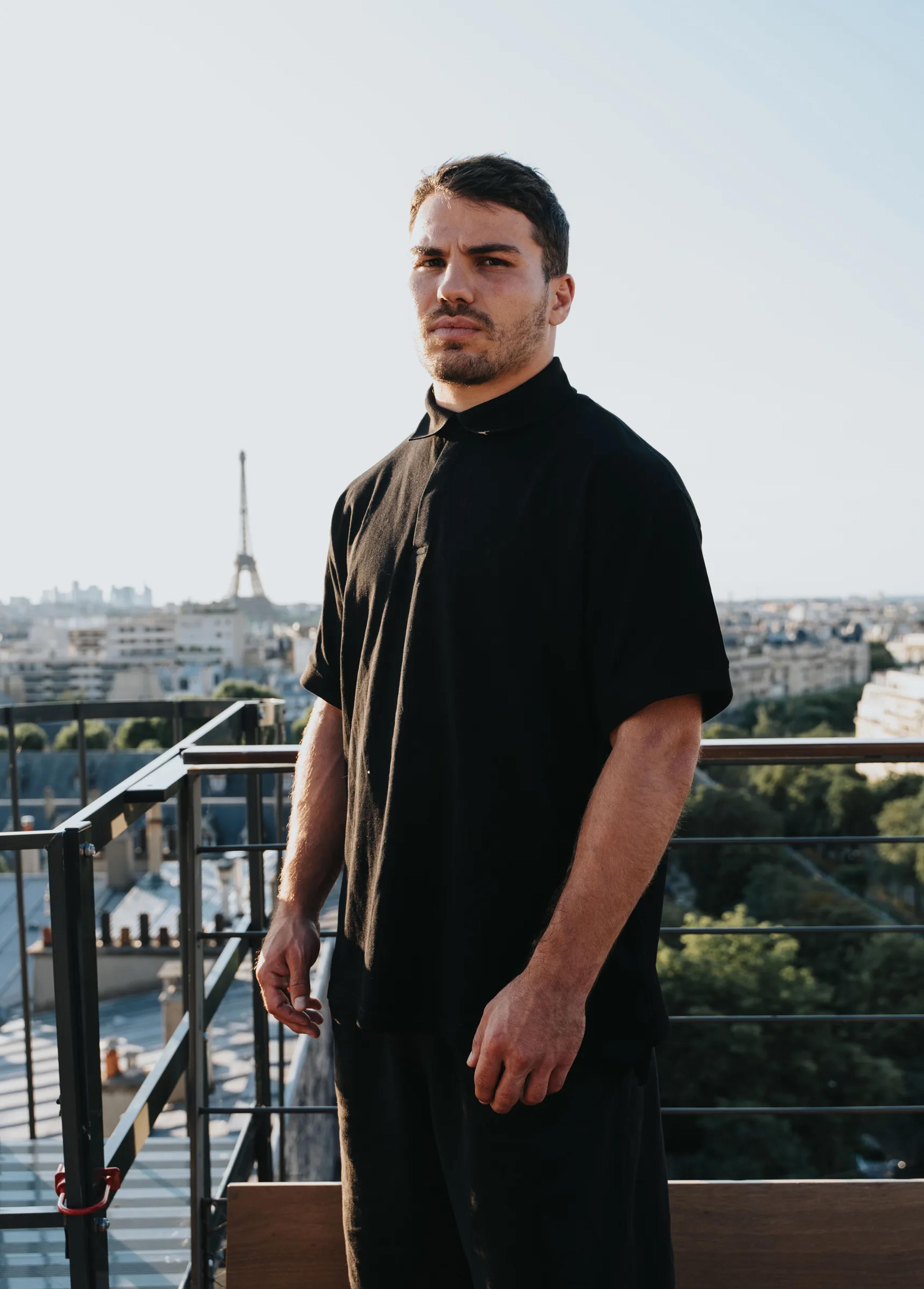A rugby player on the rooftop with the Eiffel Tower in the distance