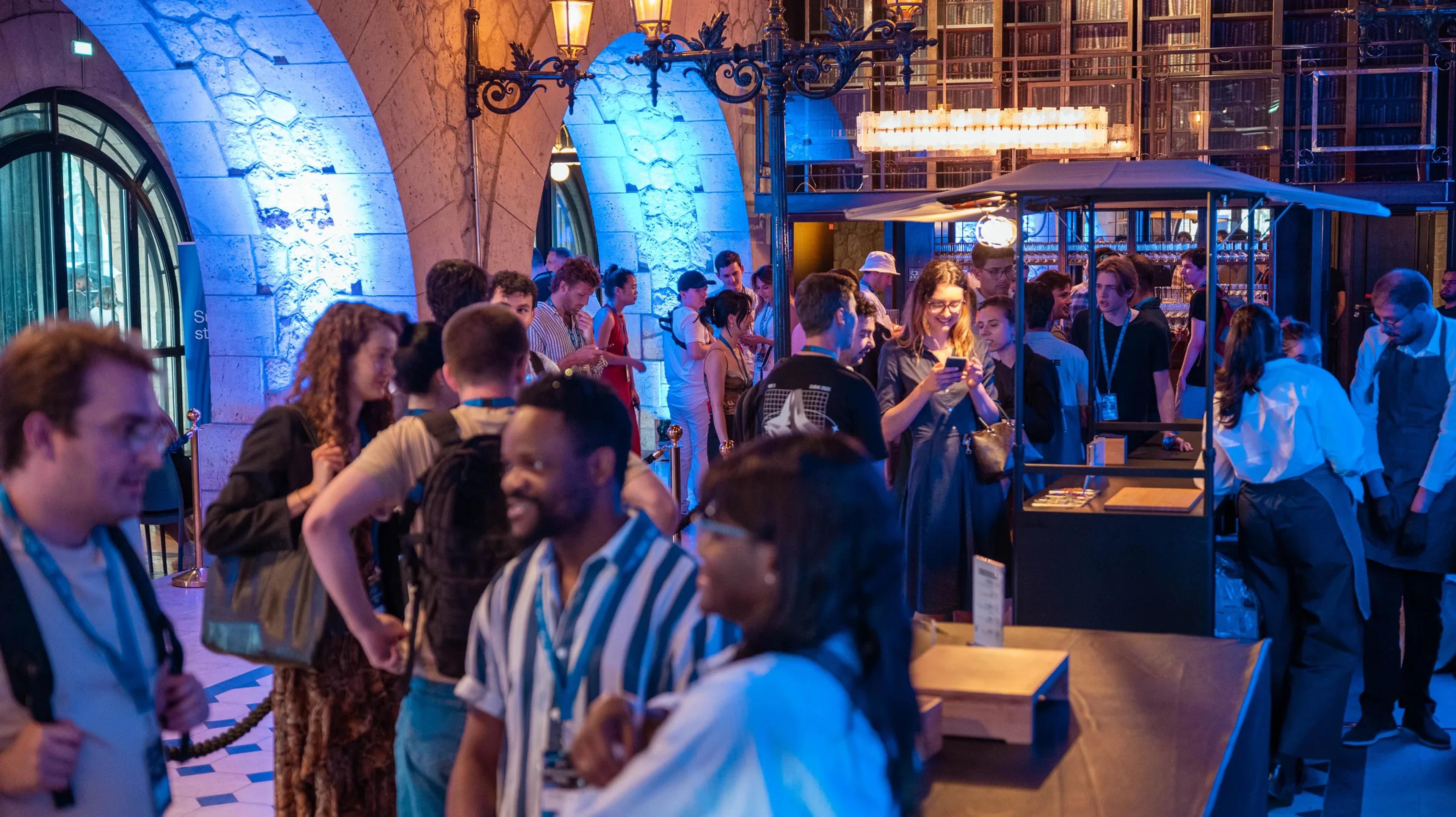 A crowd gathered around the bar in the blue-lit venue