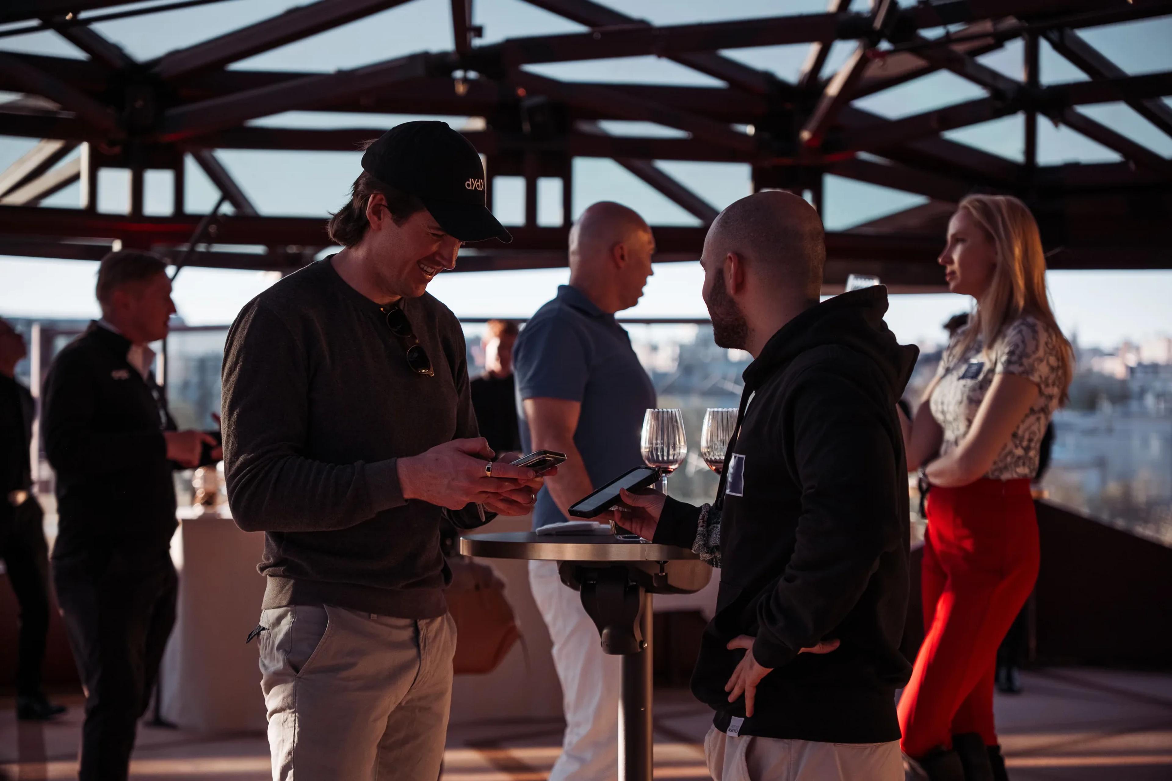 Guests mingling around a standing table on the rooftop