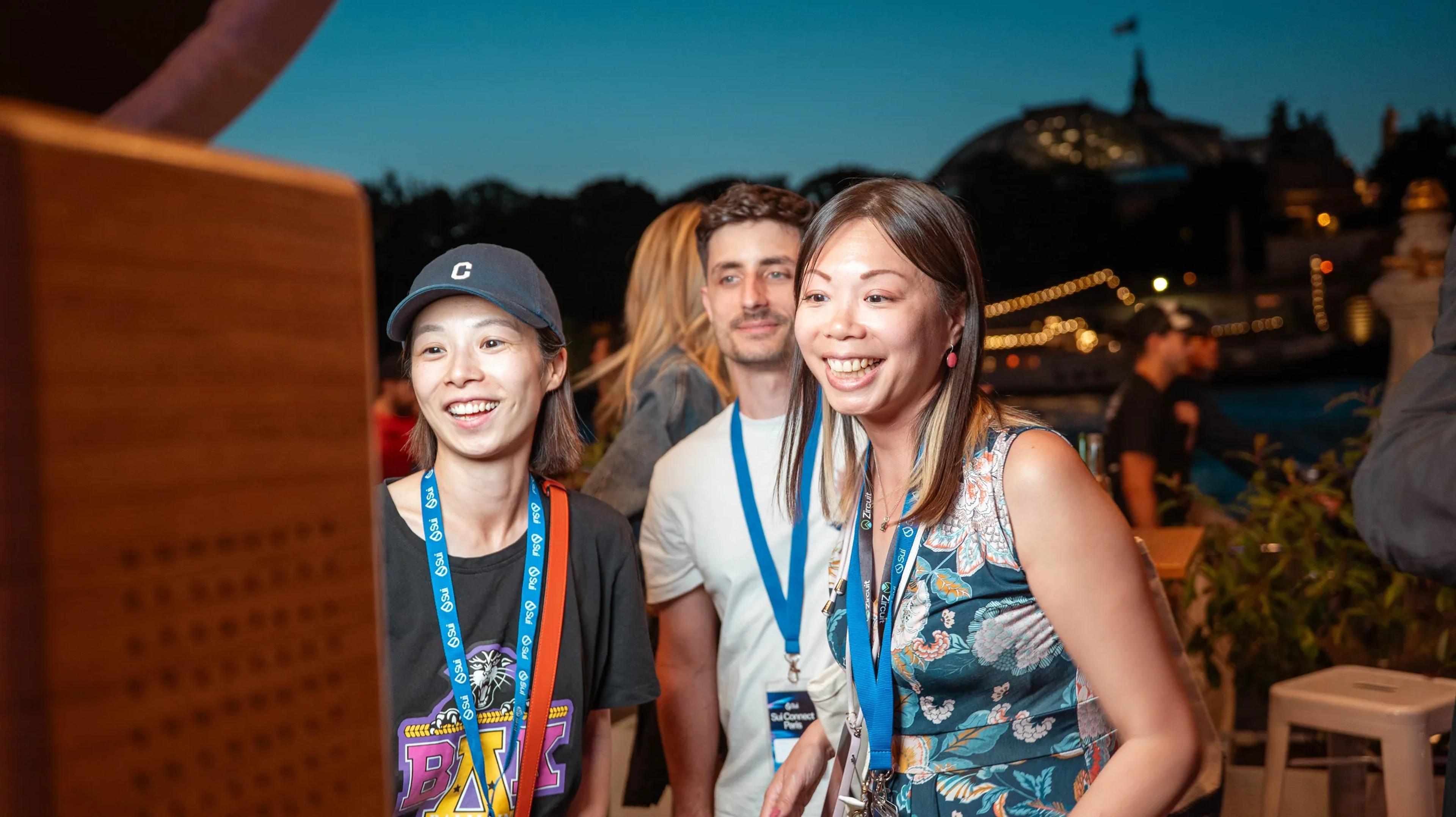 Two attendees laughing at the riverside reception at dusk
