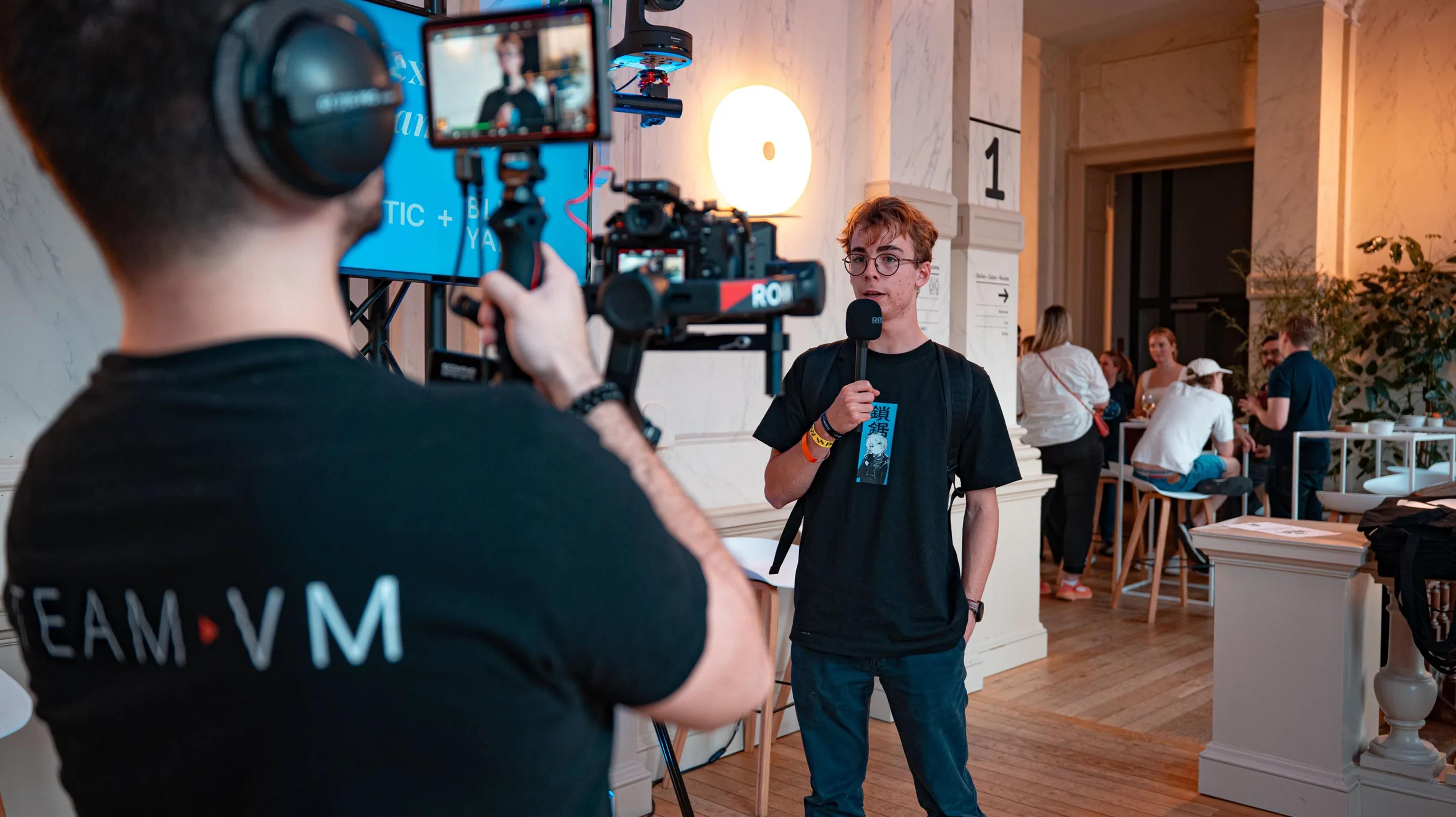 A camera operator filming an interview at the Agnostic event