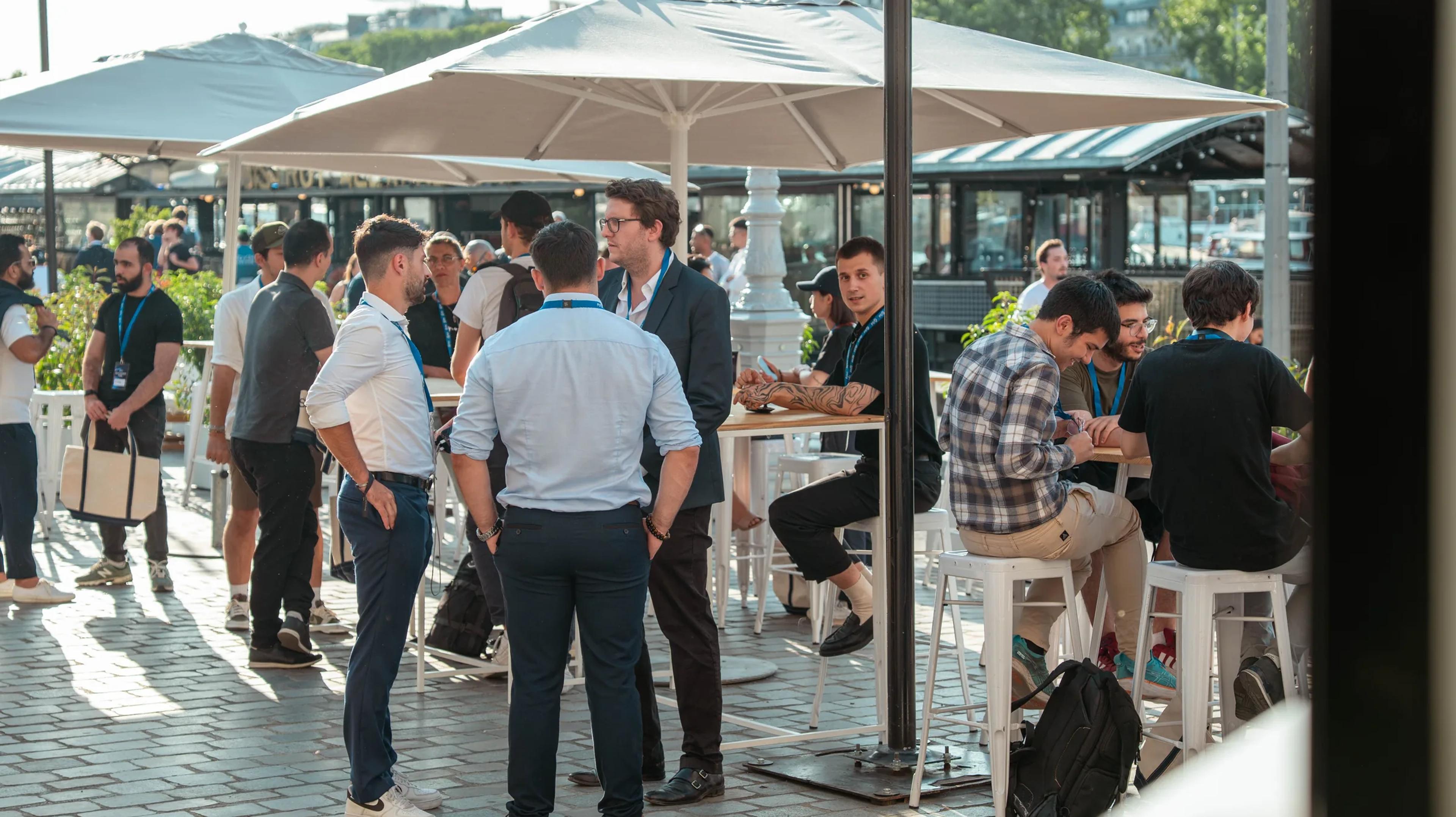 Attendees mingling under parasols on the riverside terrace