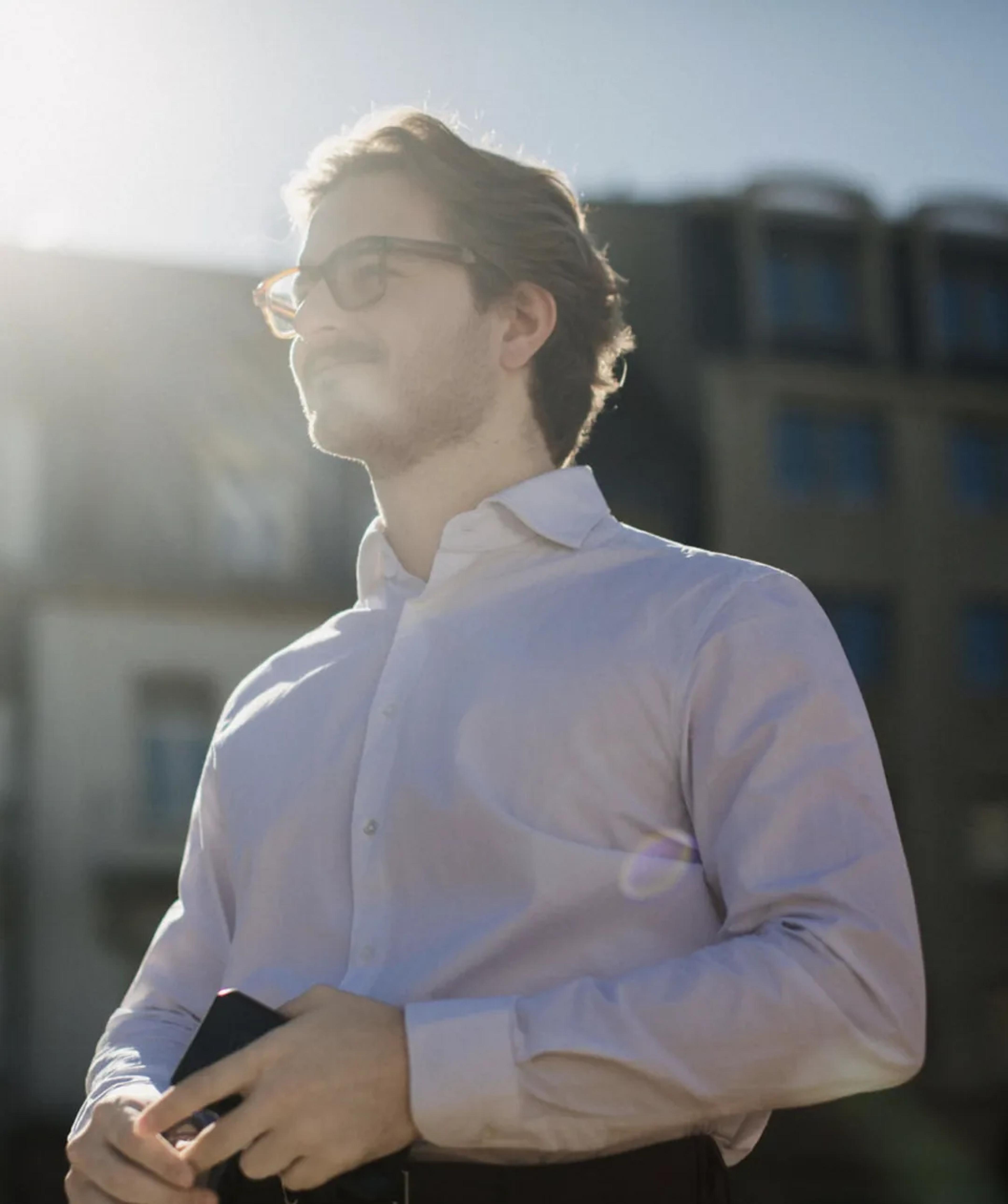 A Hash Consulting team member in a white shirt looking out across the city in the late sun.