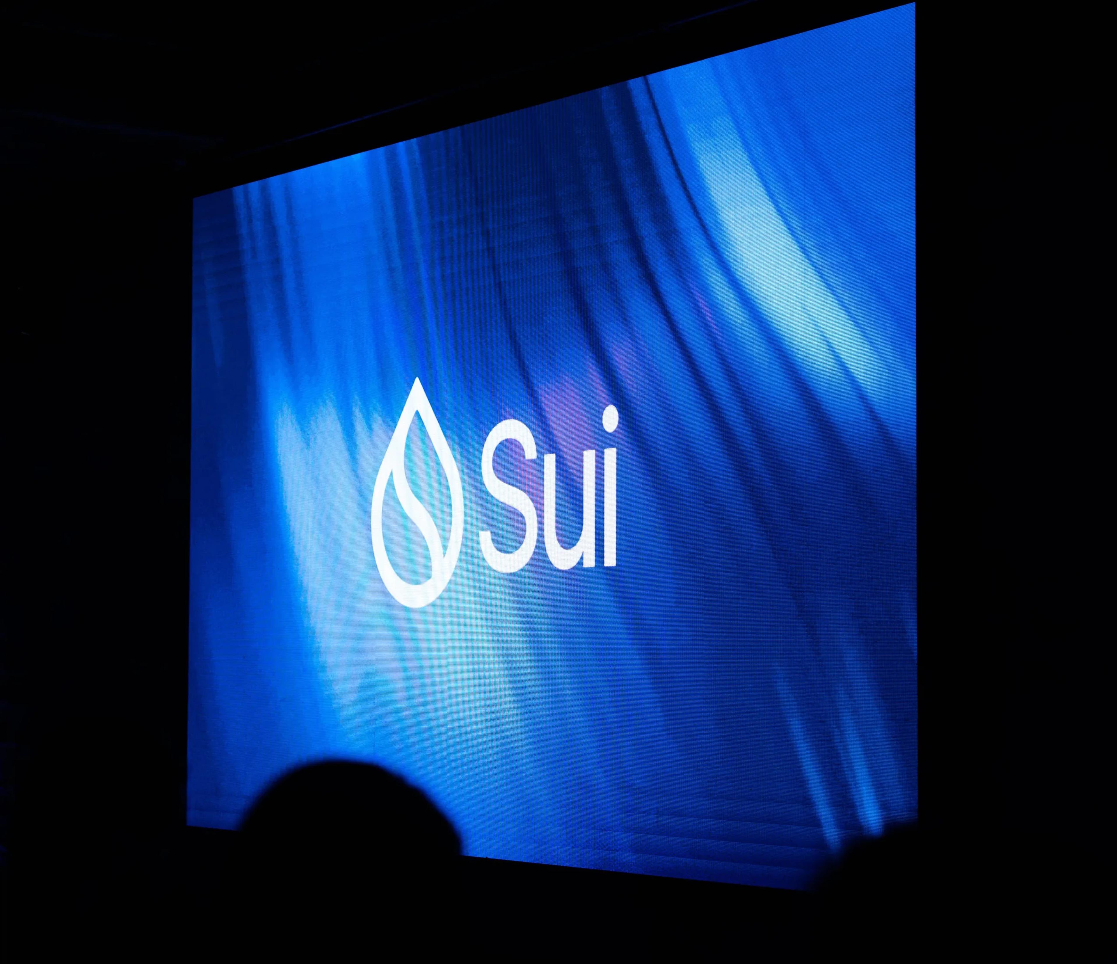The Sui logo projected on a screen in the darkened room