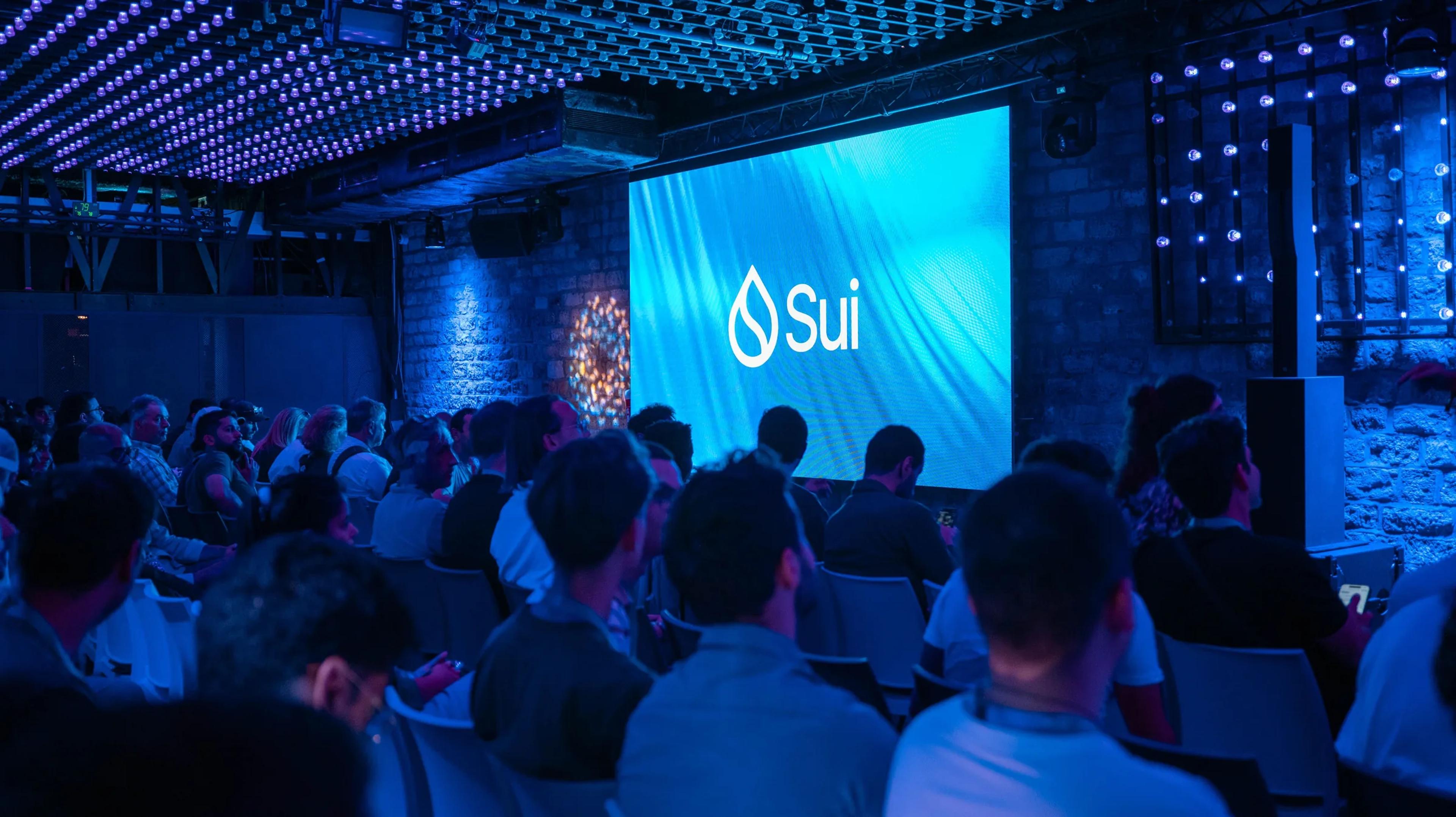 The audience facing a Sui-branded screen under the LED ceiling at Sui Connect Paris