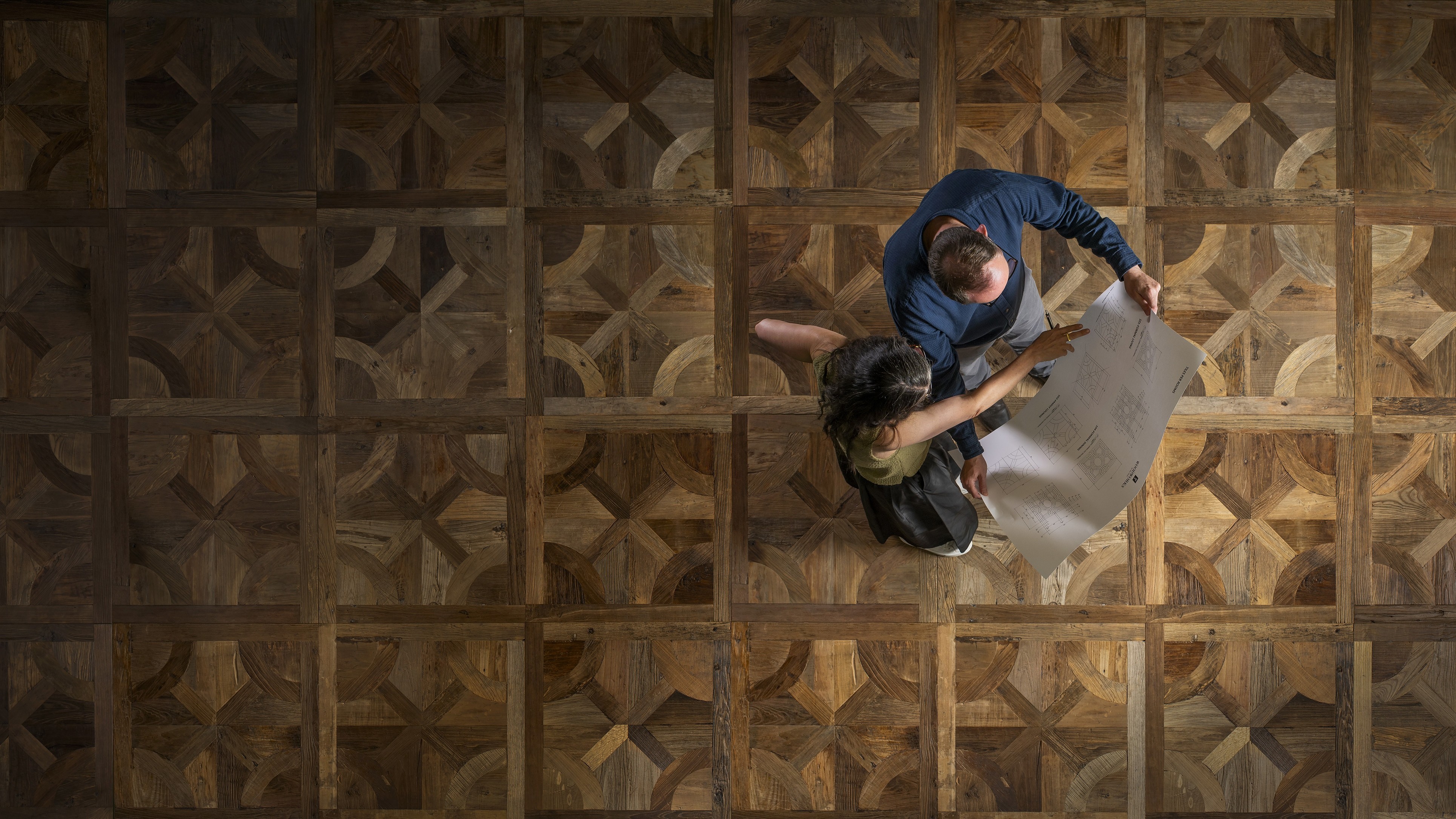 Woodworks specialists reviewing plans on a parquet floor
