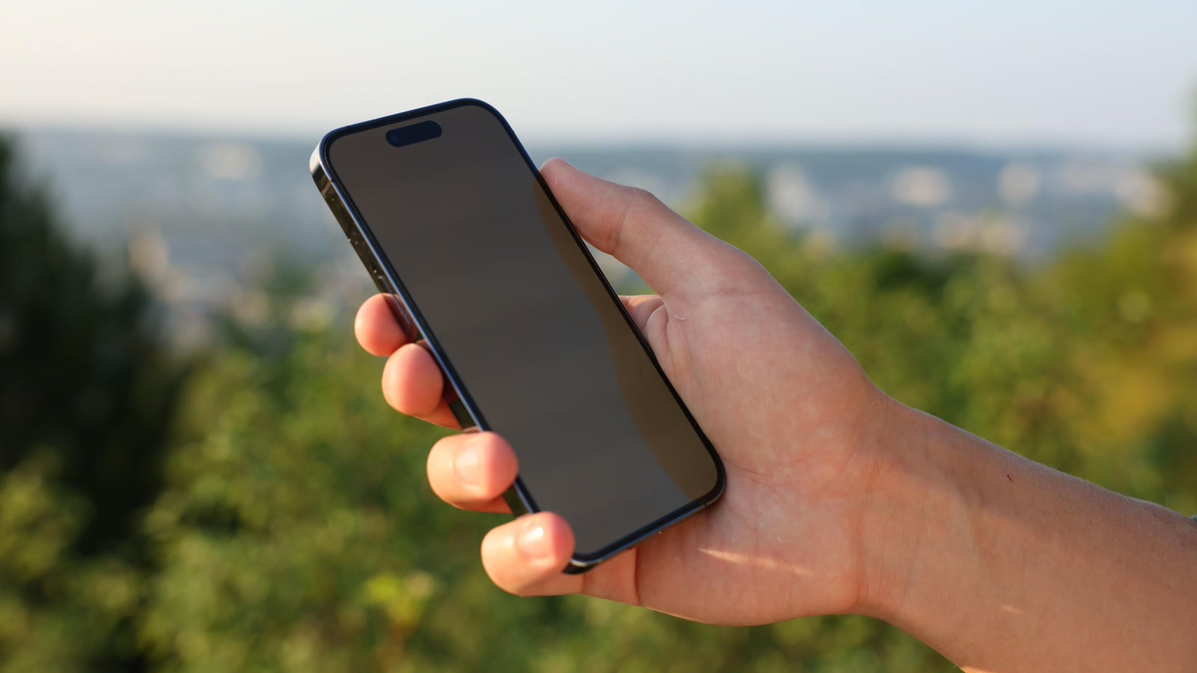 Hand holding a smartphone outdoors — mobile softphone push notifications on the go