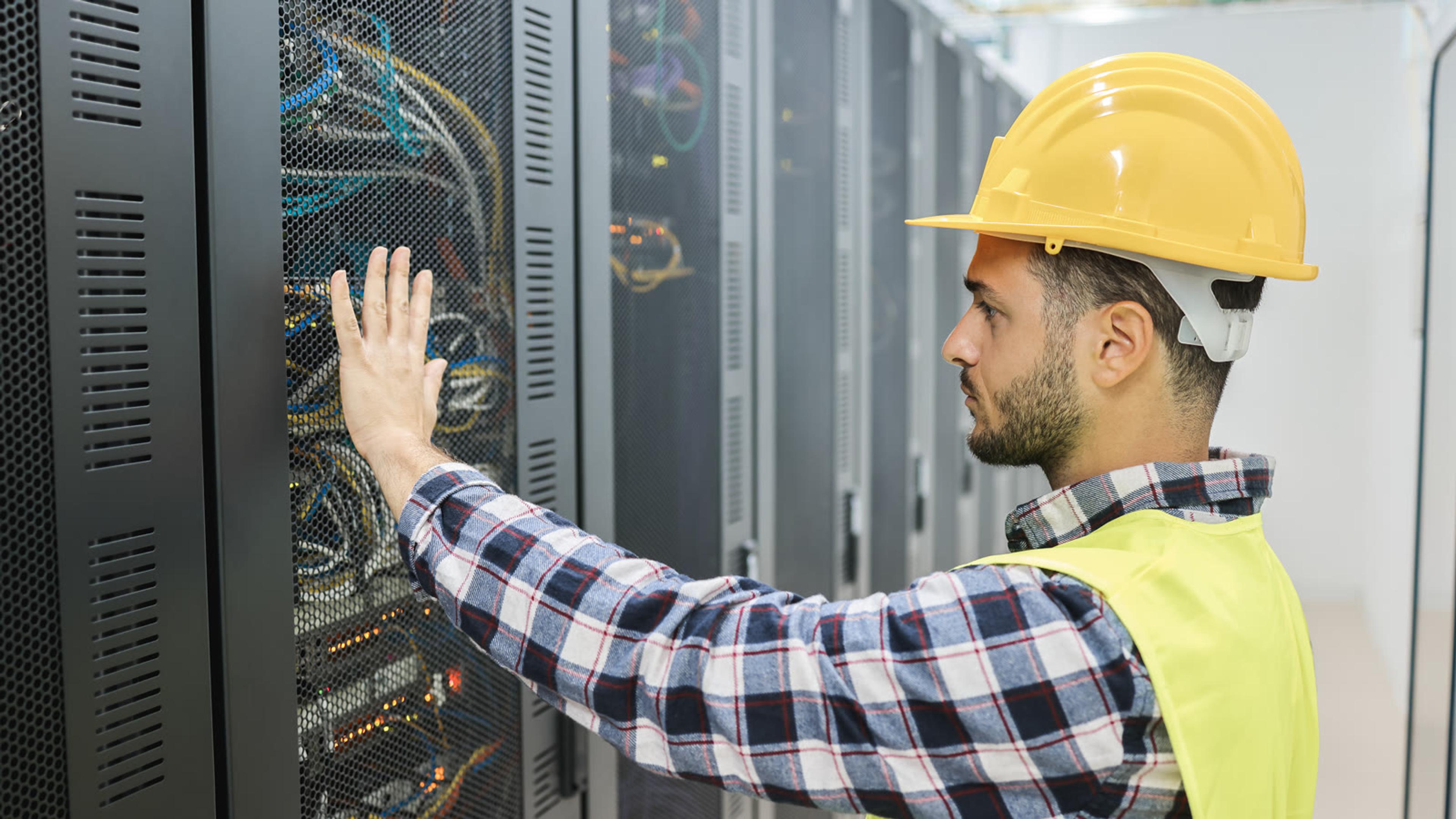 Technician inspecting server racks in a data centre