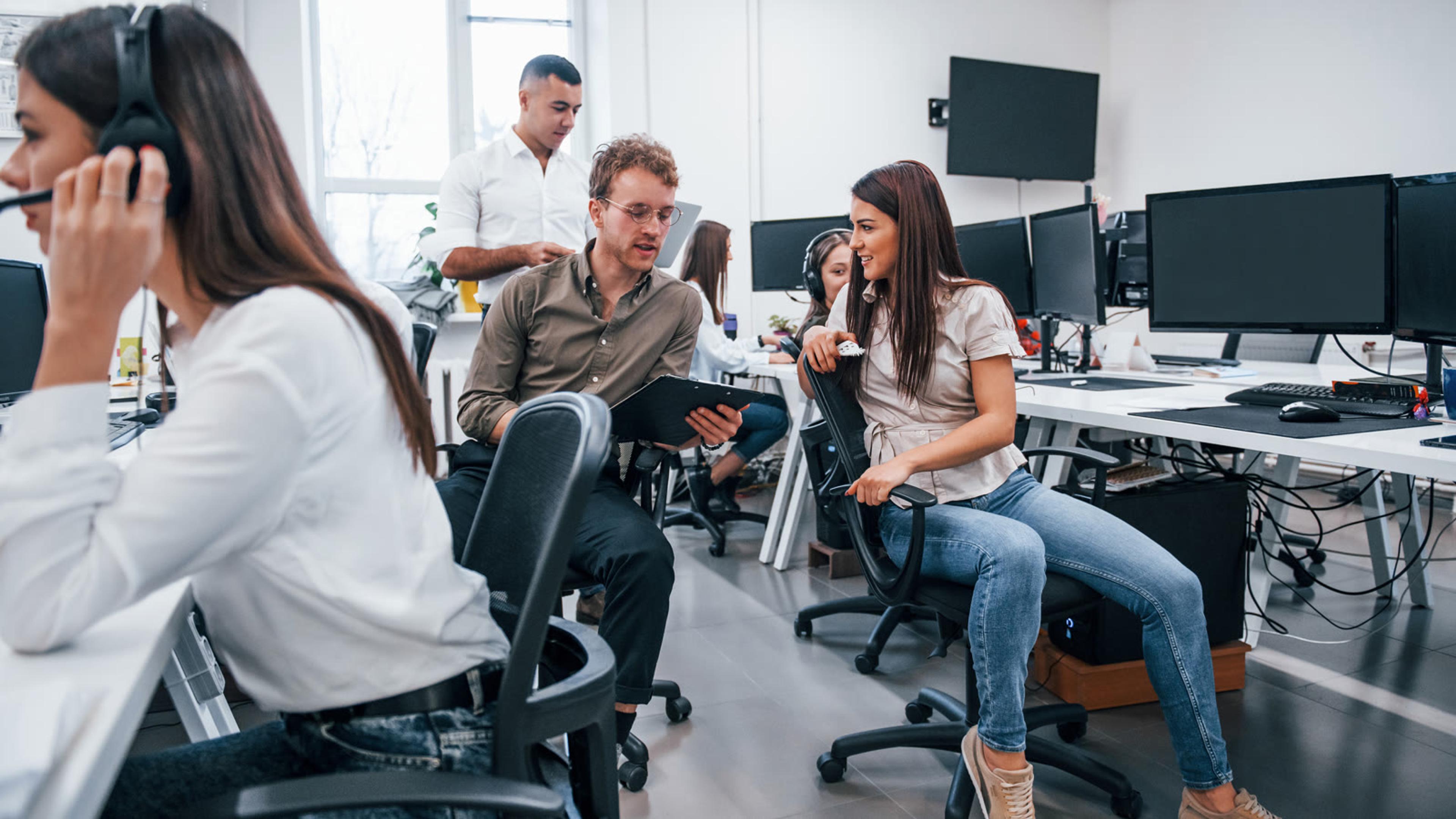 Office team at computers with headsets taking calls on a managed business softphone