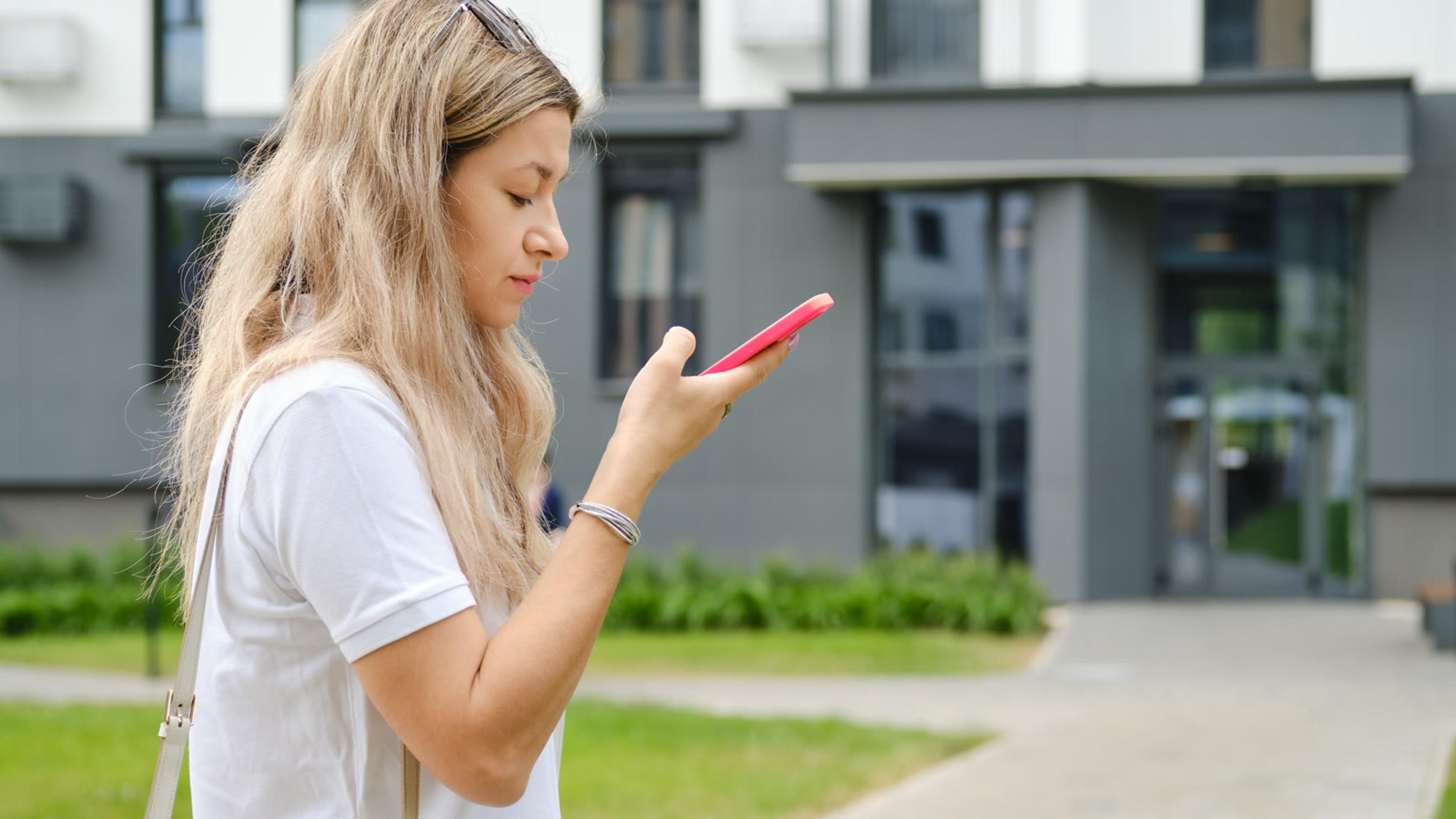 Mobile estate agent outdoors using a phone near residential property